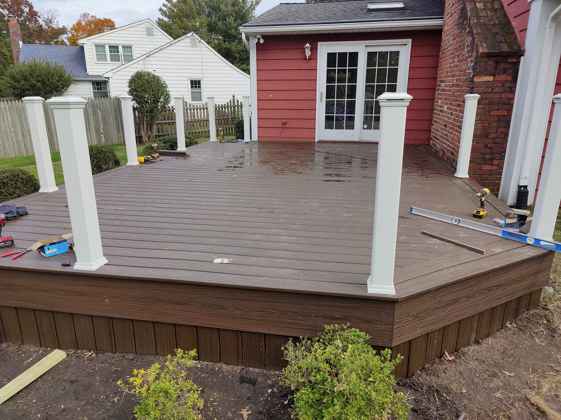 A deck is being built in front of a red house.