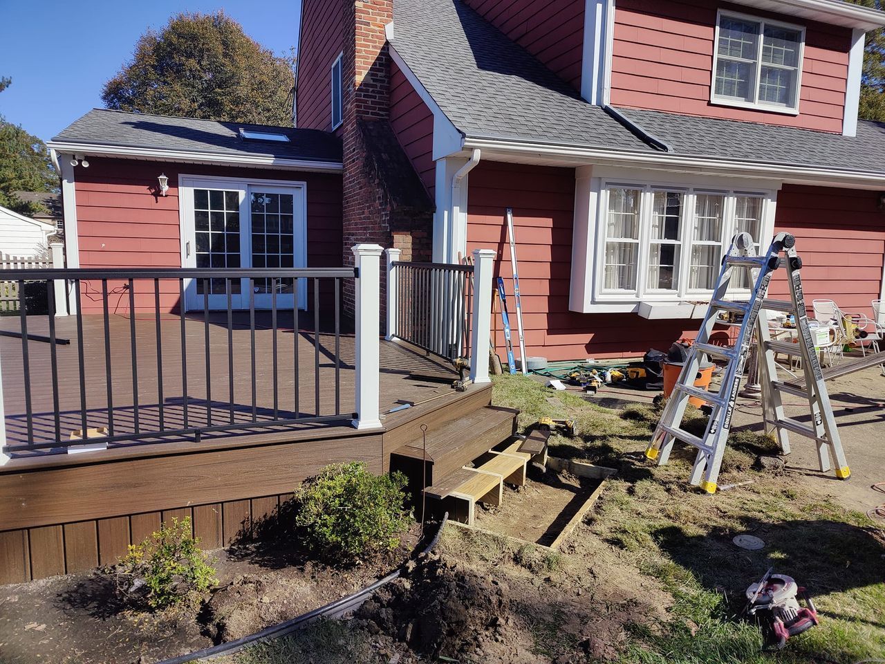 A red house with a deck and a ladder in front of it.