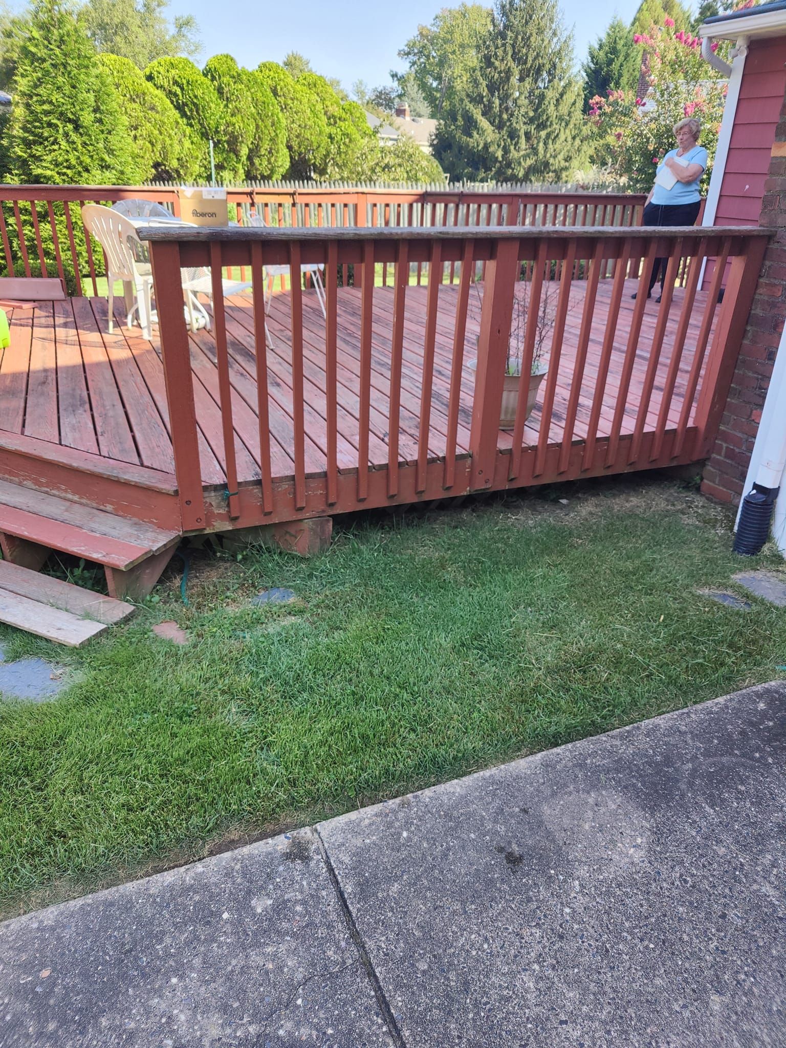A man is standing on a wooden deck next to a house.