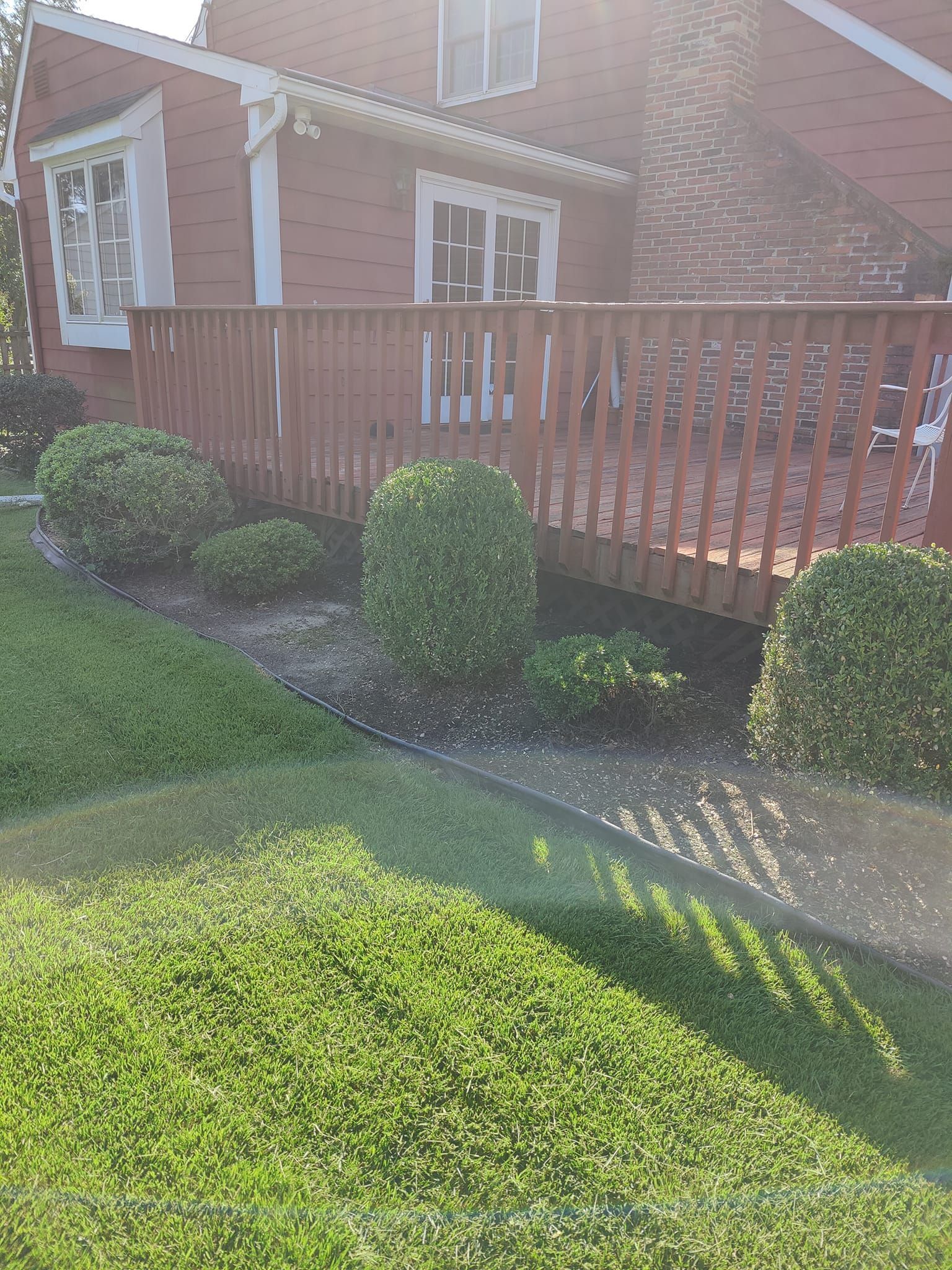 A brick house with a wooden deck and a walkway leading to it.