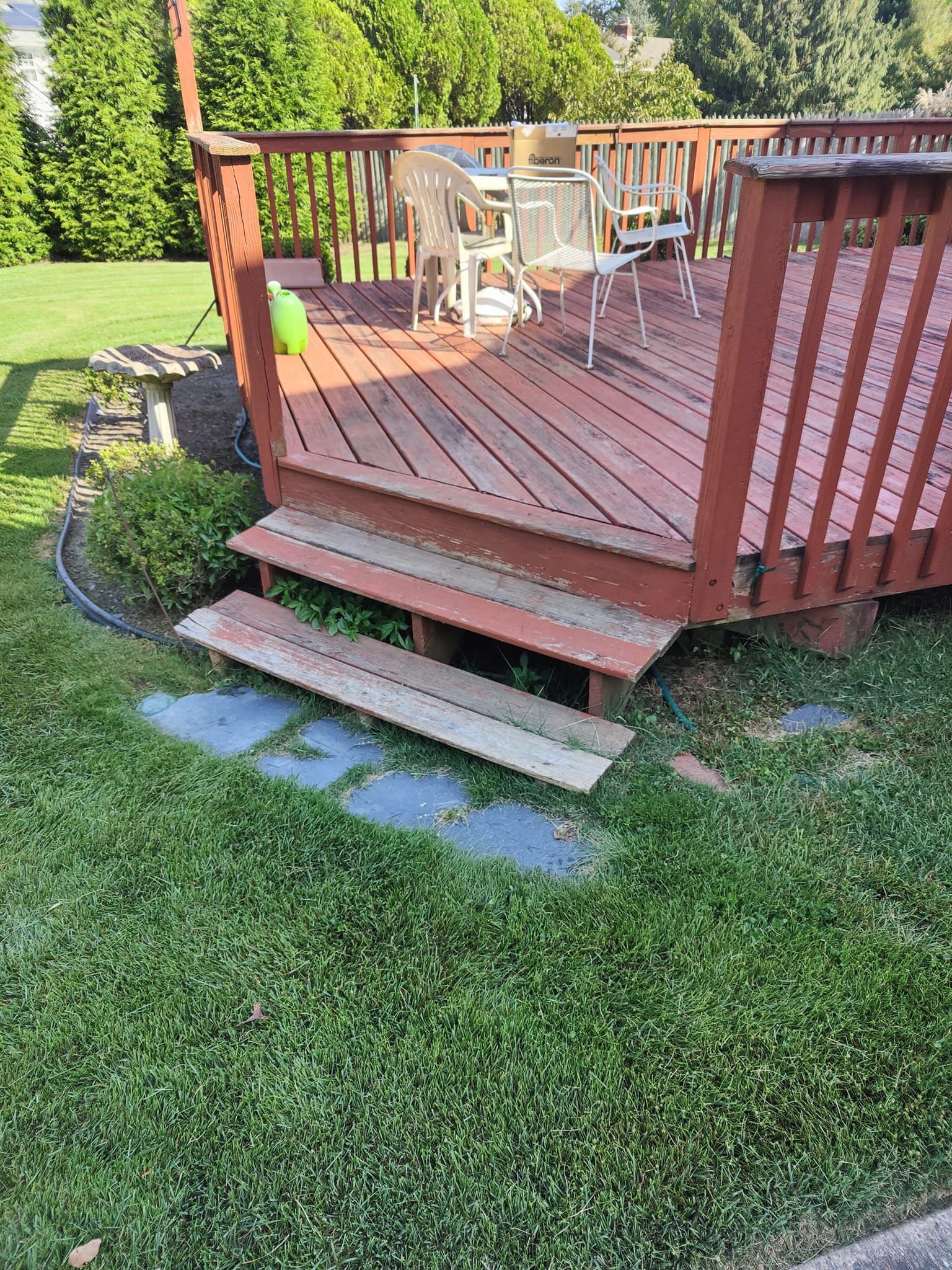 A wooden deck with stairs leading up to it in a yard.