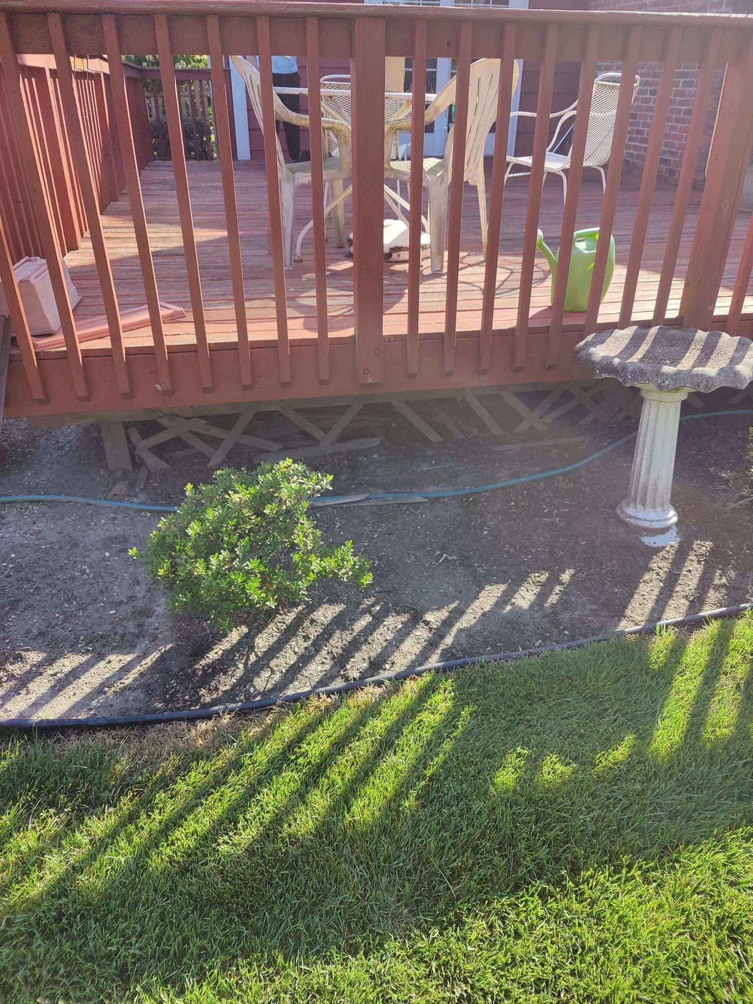 A wooden deck with a bird bath in front of it.