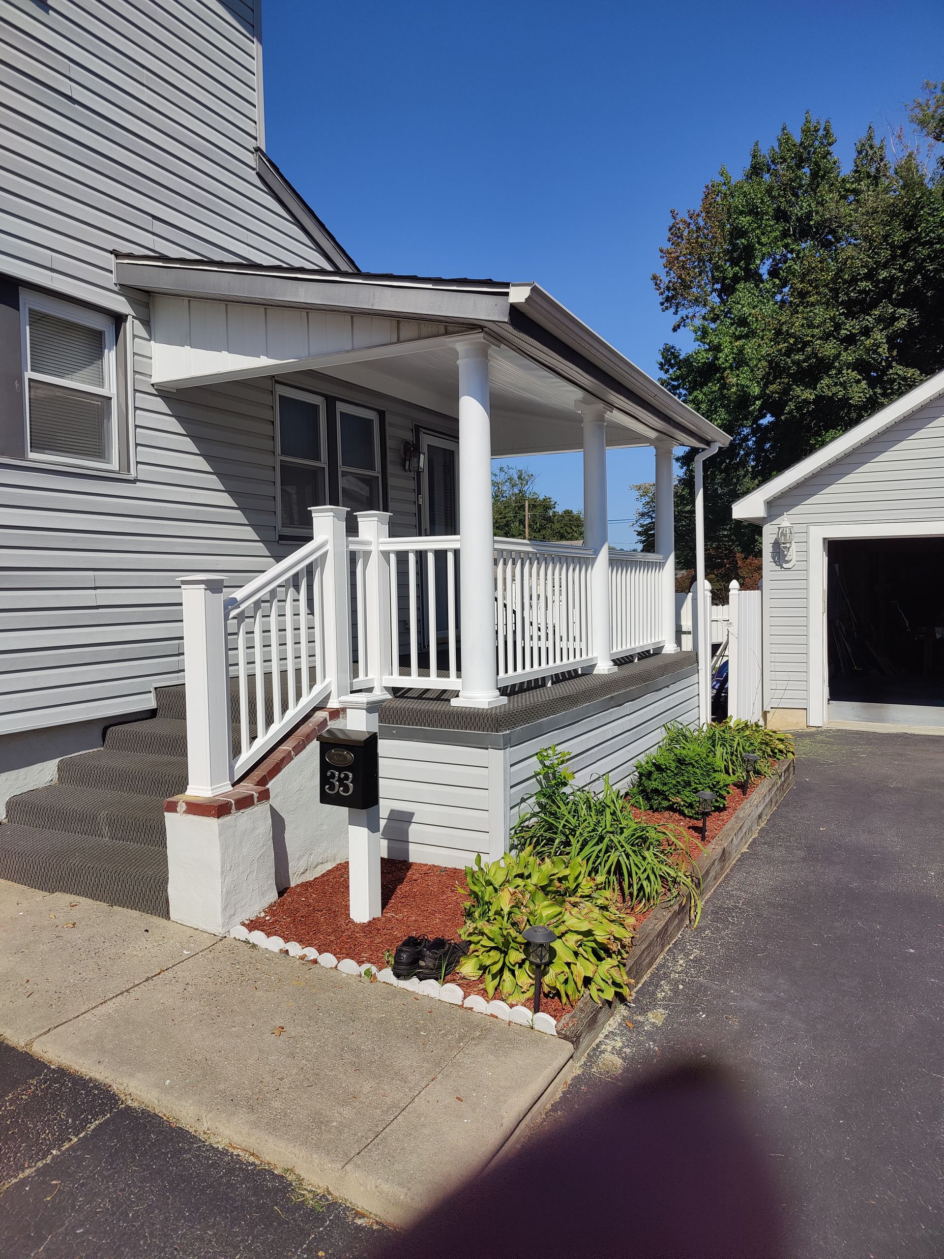 A white house with a porch and a mailbox in front of it.