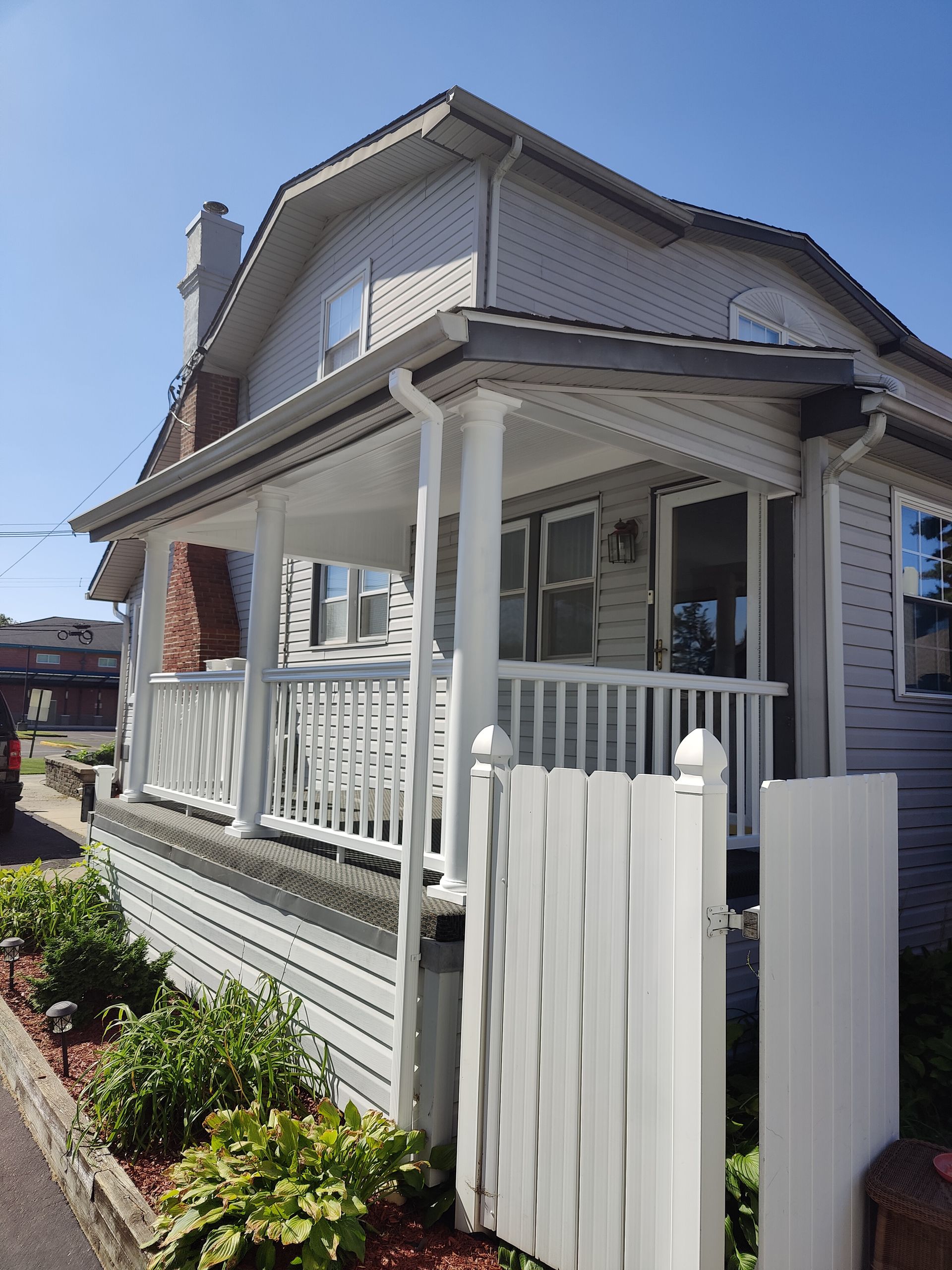 A white house with a porch and a white picket fence.