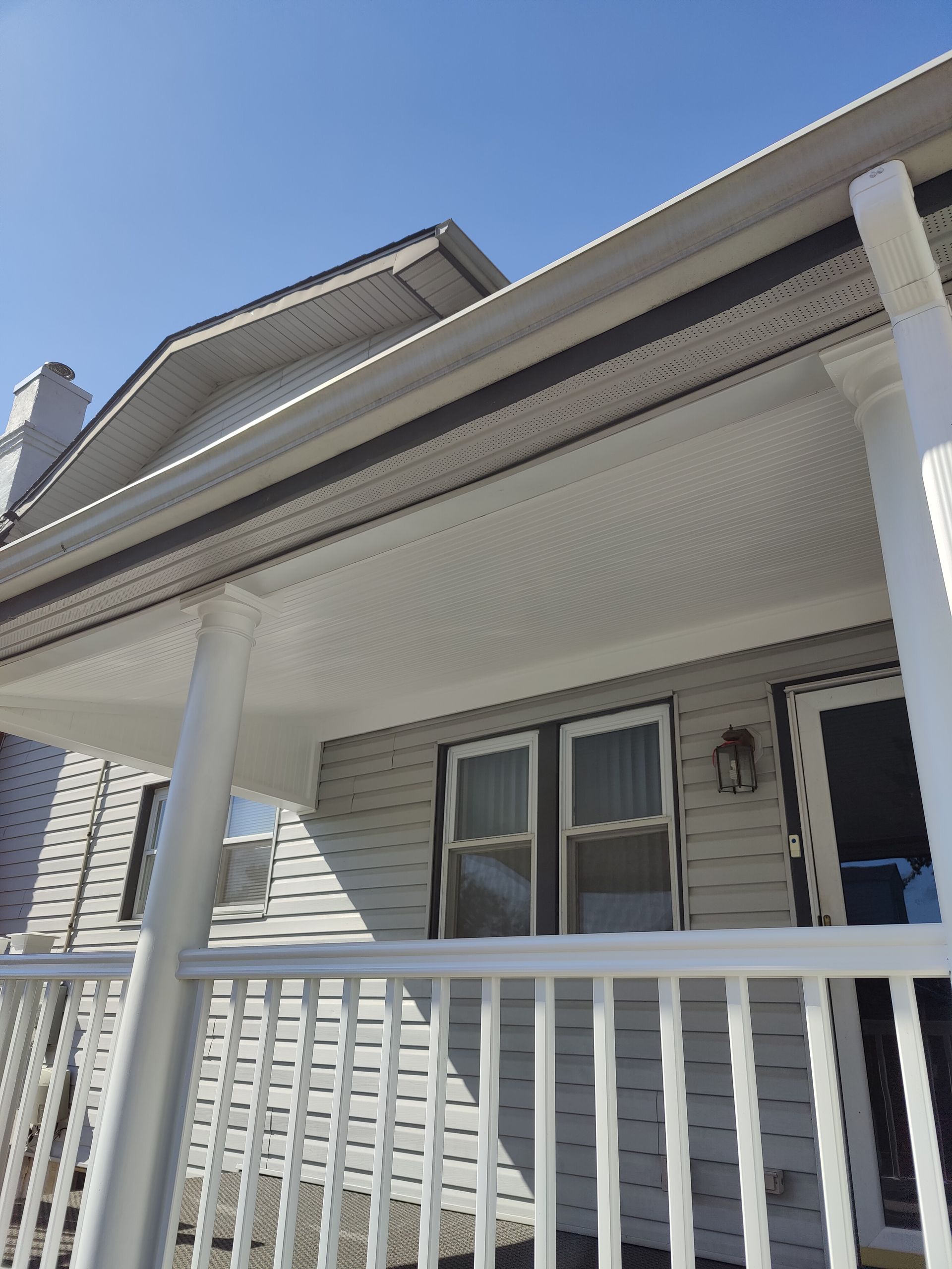 A white house with a porch and a blue sky in the background.