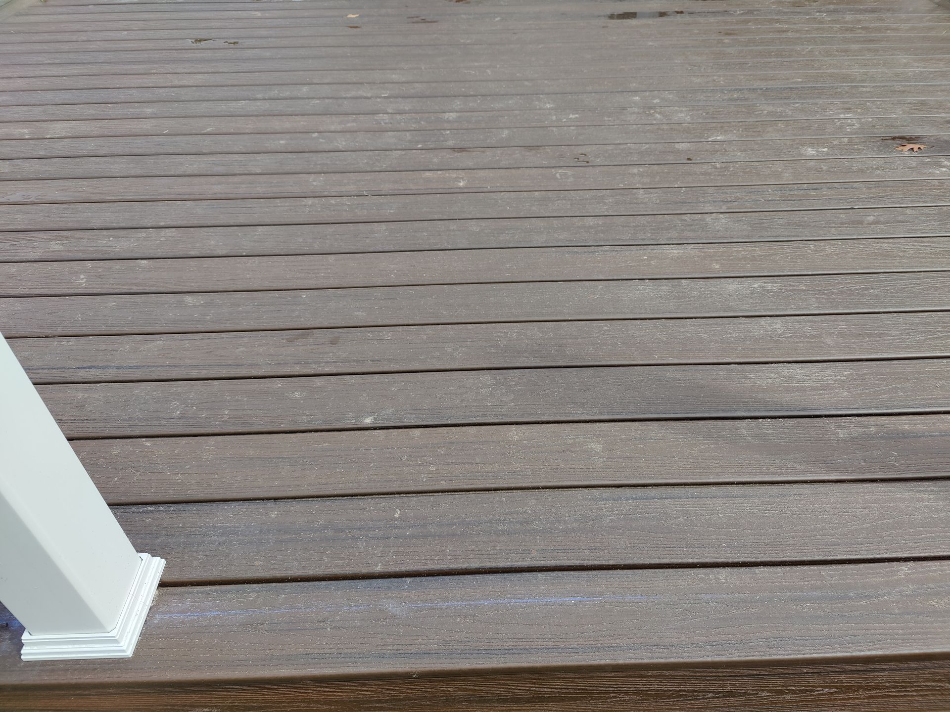 A close up of a wooden deck with a white railing.