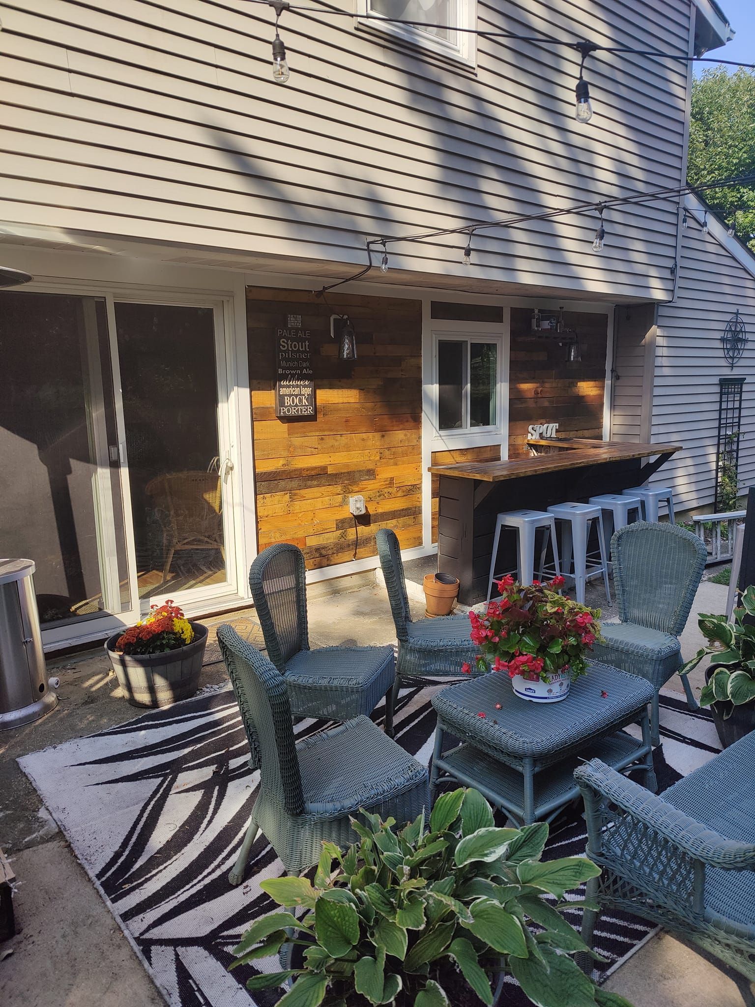 A patio with wicker furniture and a rug in front of a house.