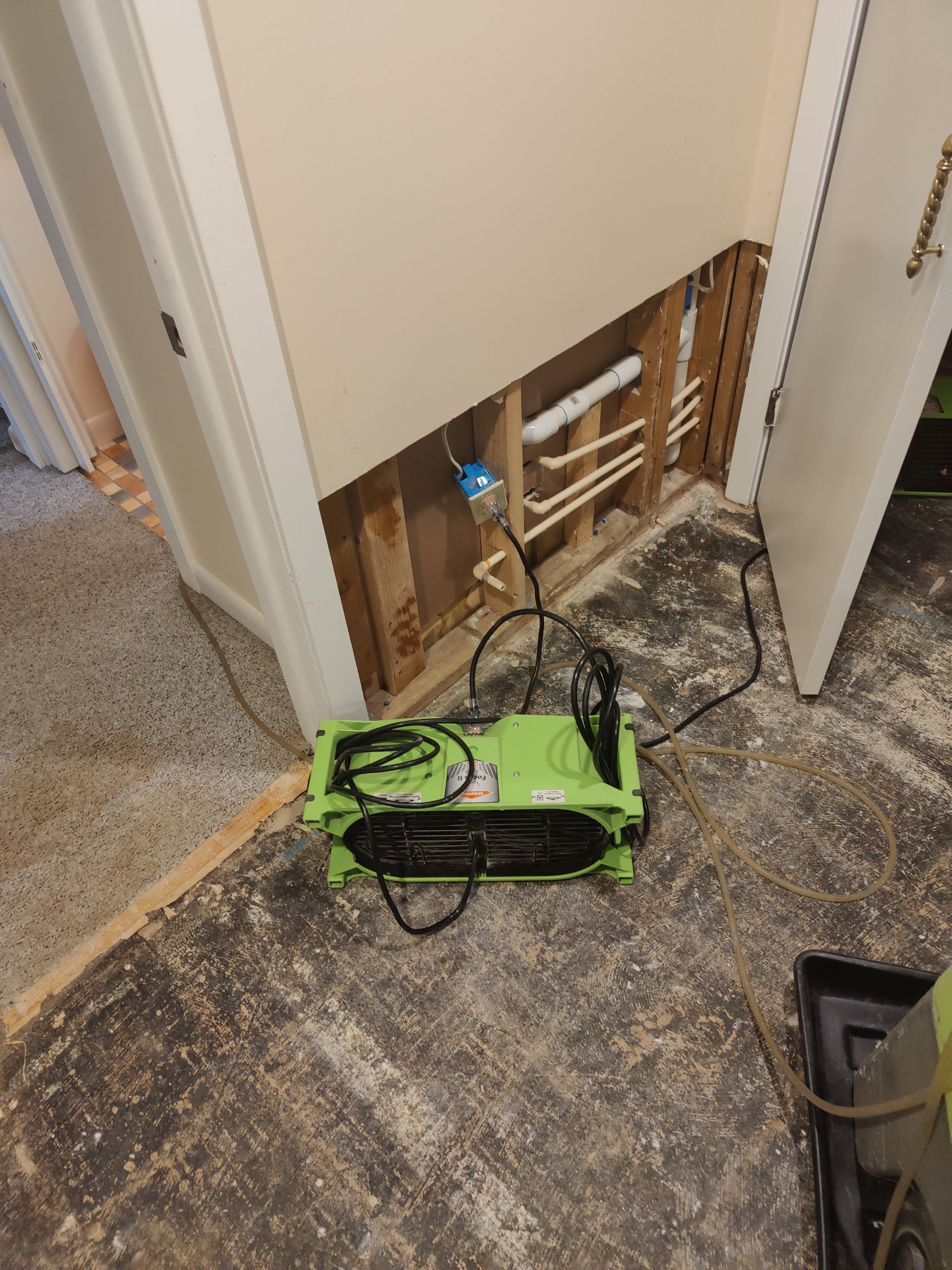 A green box is sitting on the floor next to a door.