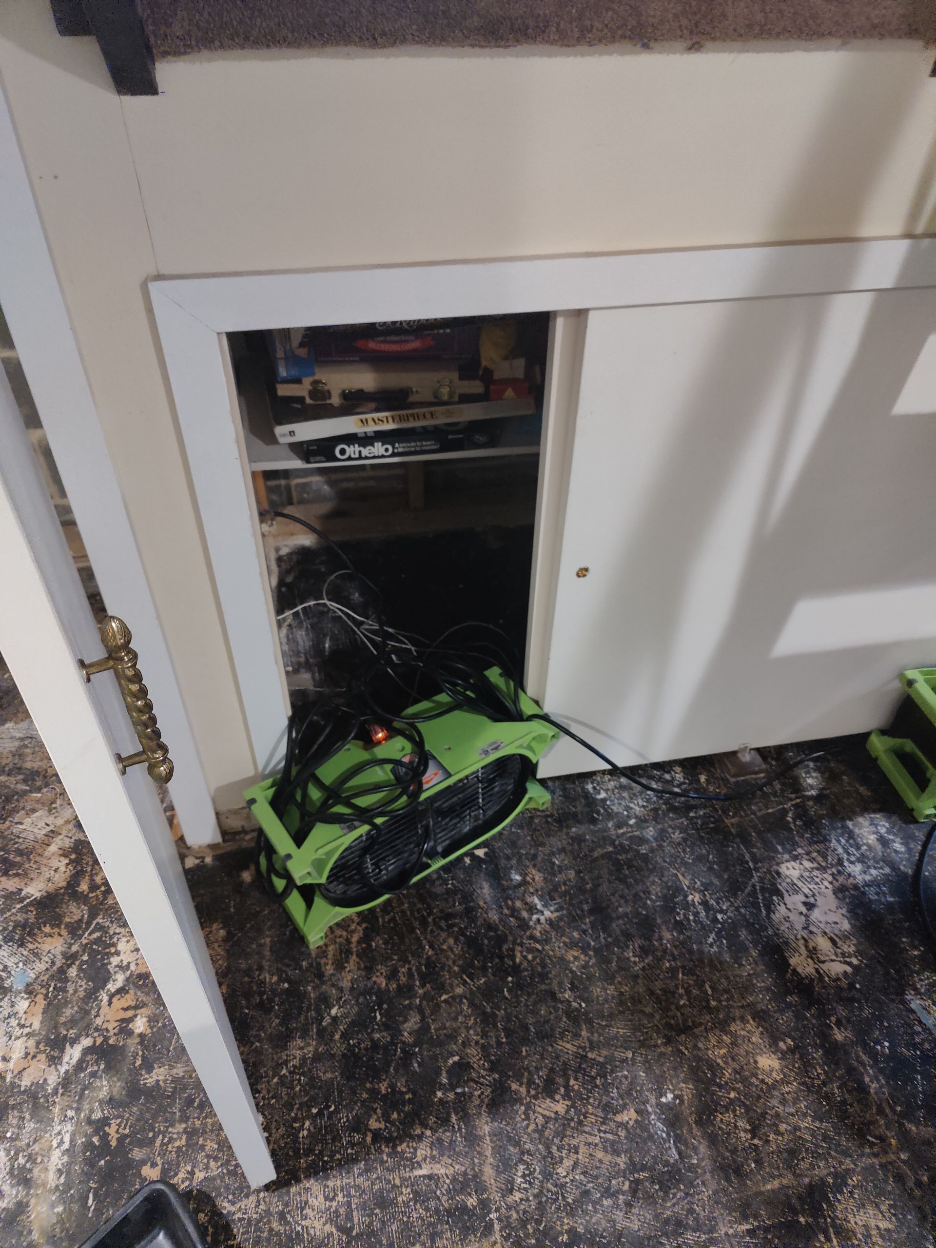 A green fan is sitting in a closet next to a door.