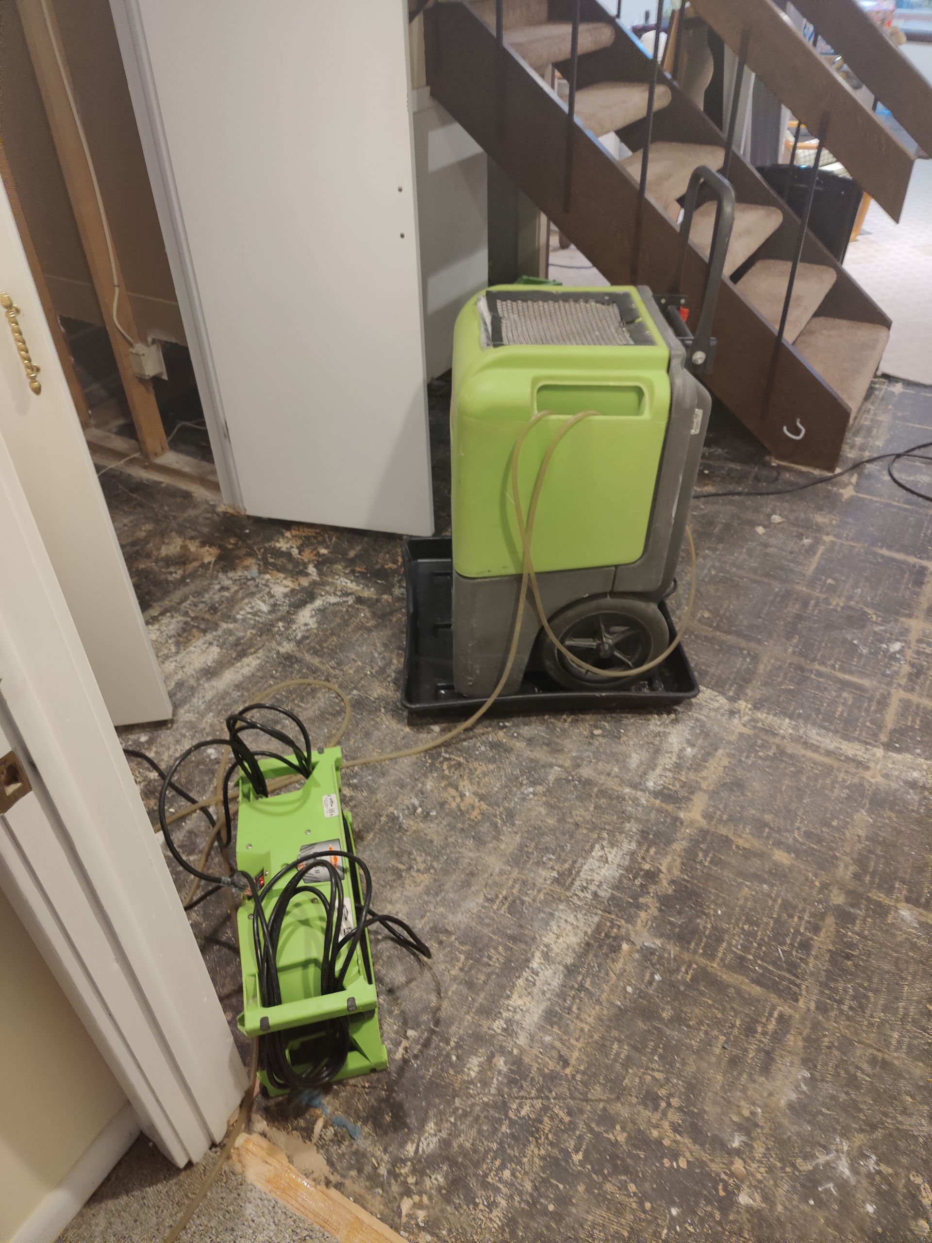 A green machine is sitting on the floor next to a staircase.