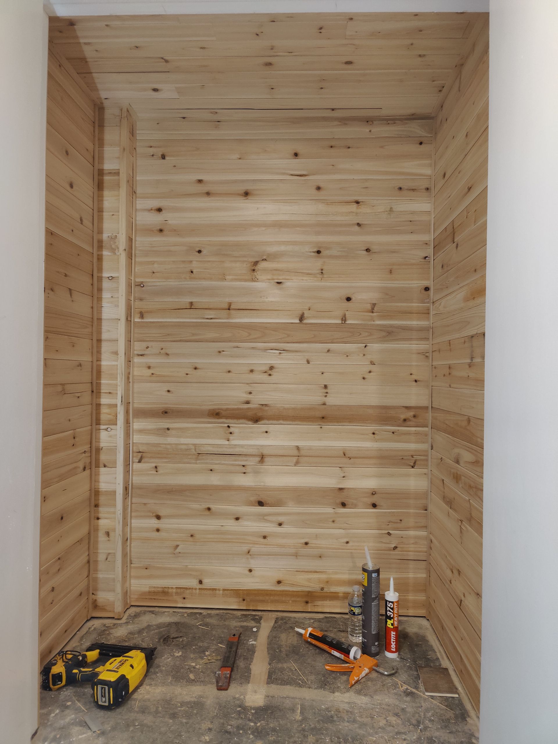 A room with wood paneling and tools on the floor.