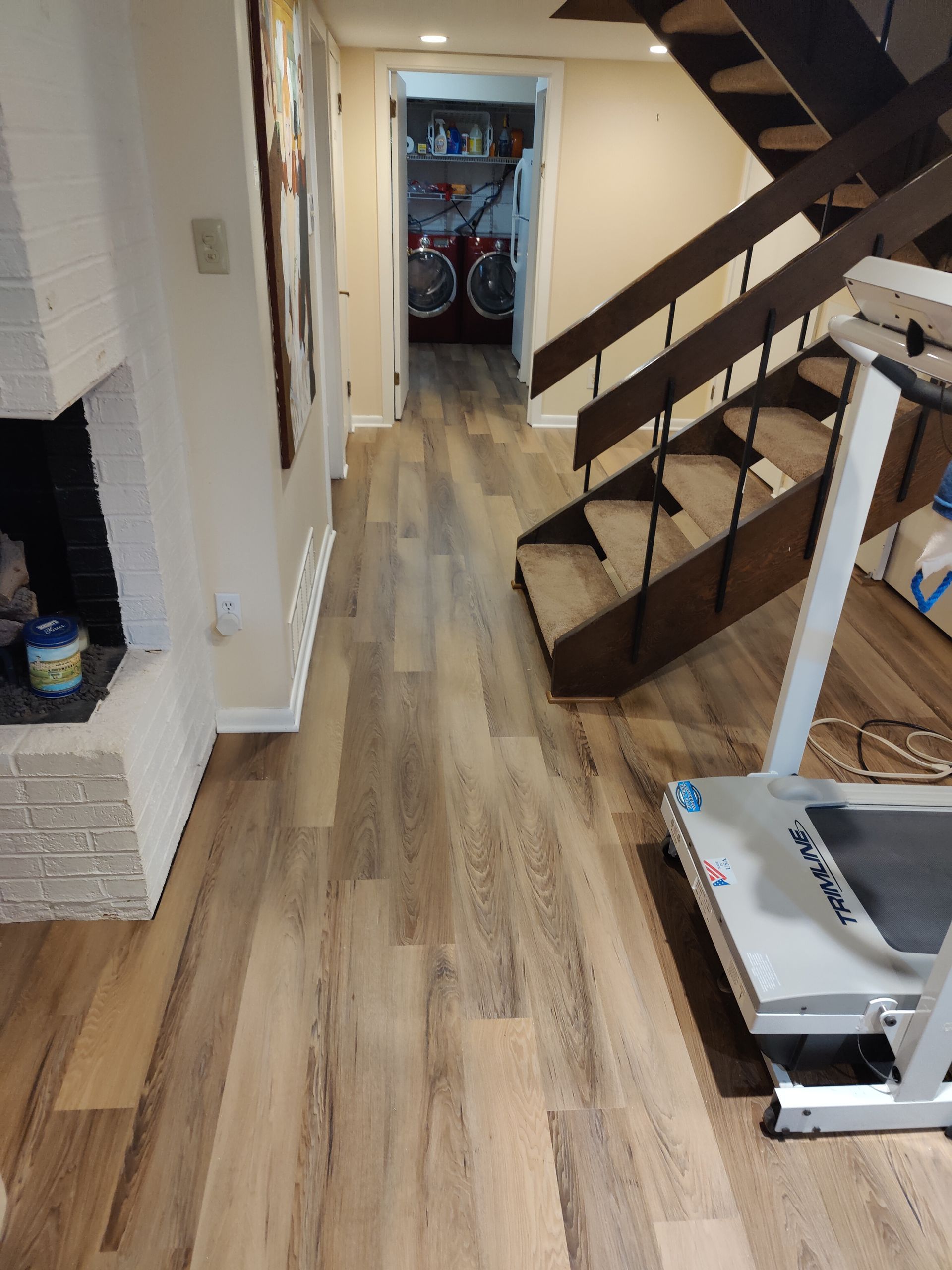 A treadmill is sitting in a hallway next to stairs.