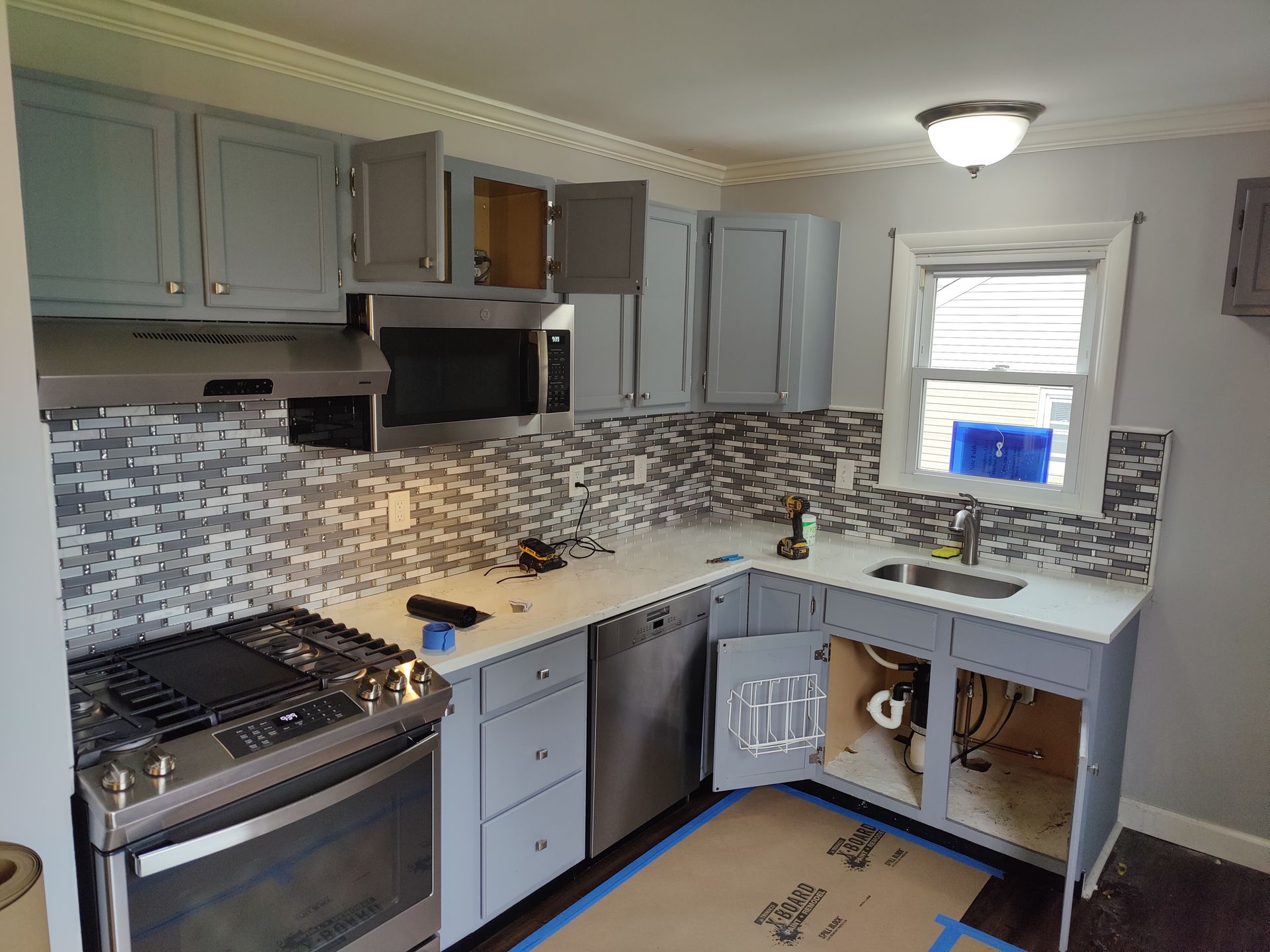 A kitchen with gray cabinets and a window.