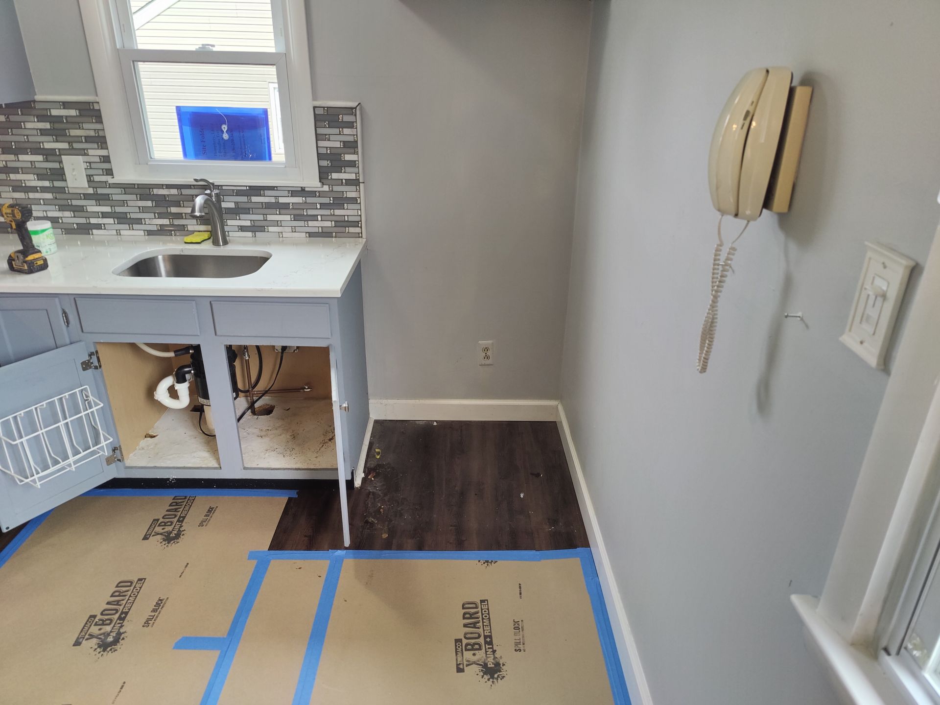 A kitchen with a sink and a phone on the wall.