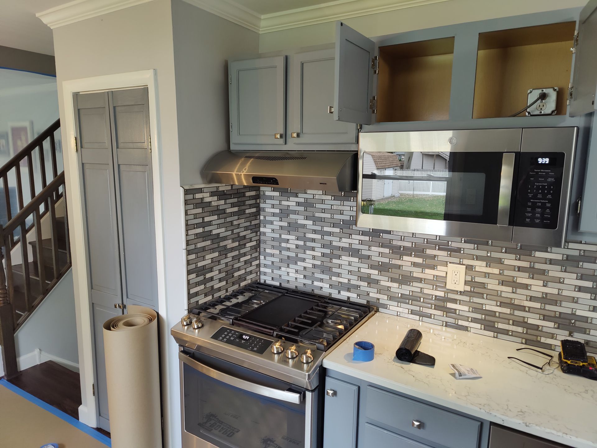 A kitchen with stainless steel appliances and gray cabinets.