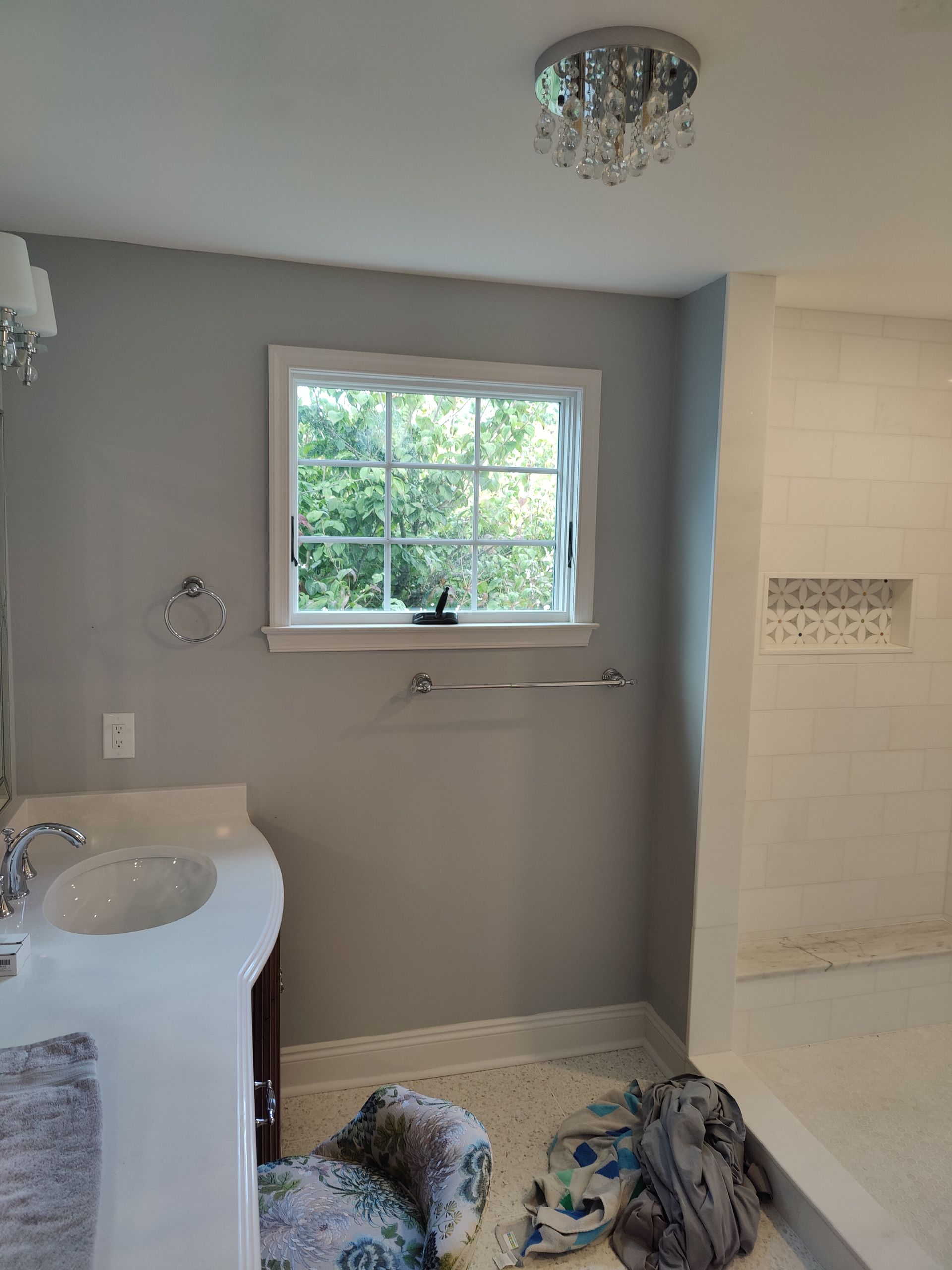 A bathroom with a sink , shower , and window.