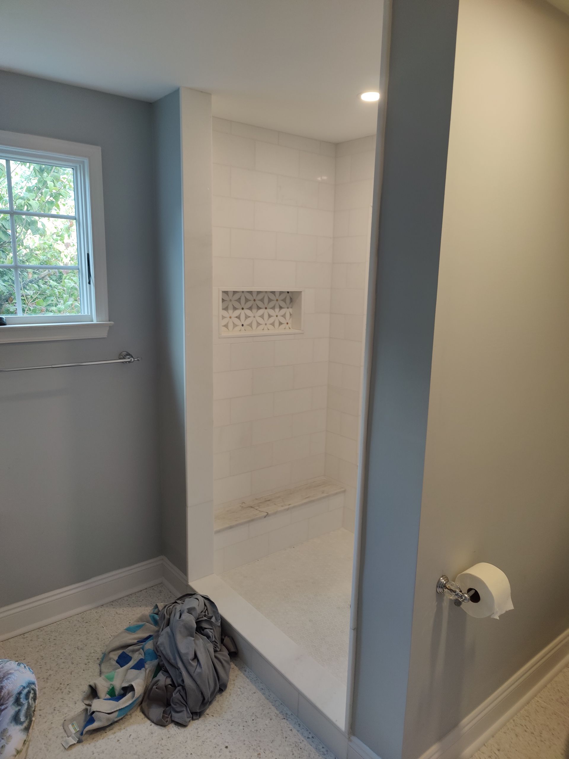 A bathroom with a walk in shower and a window.