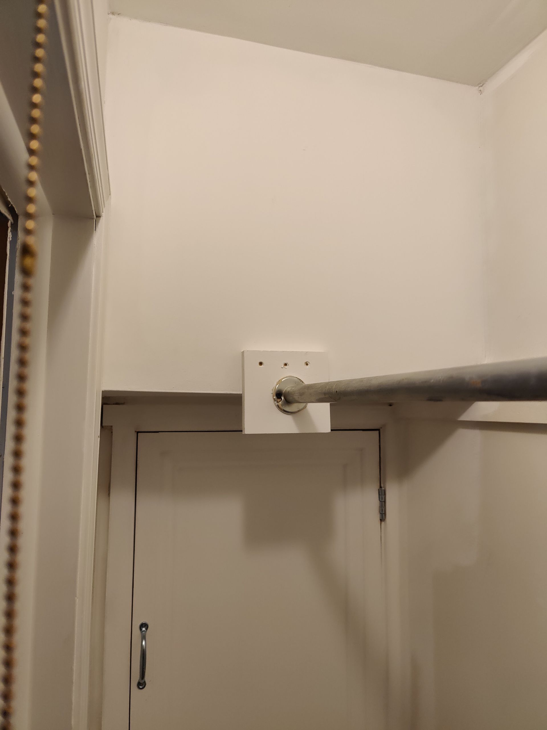 A shower curtain rod is hanging on the wall above a door.