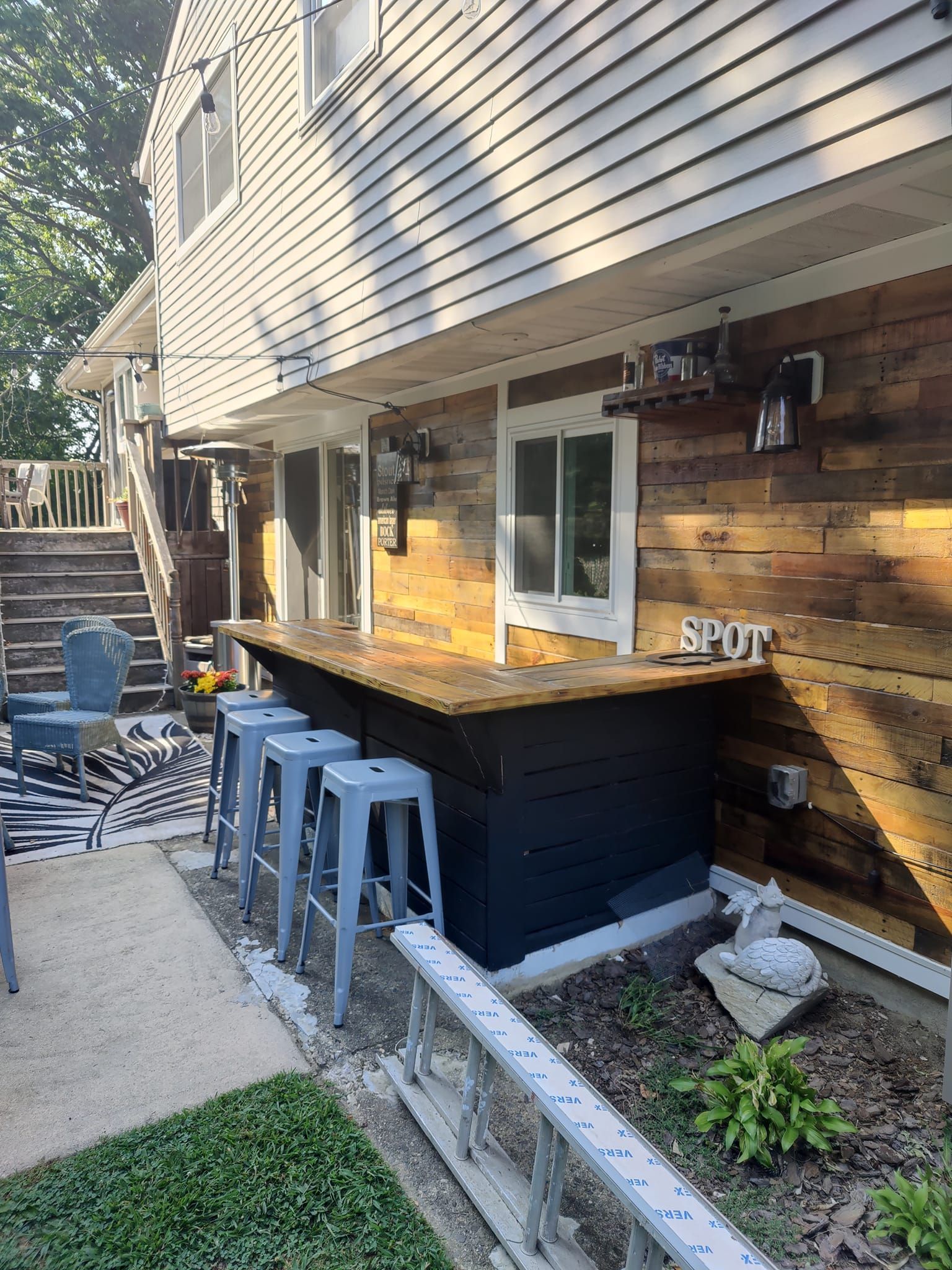 A backyard with a bar and stools in front of a house.