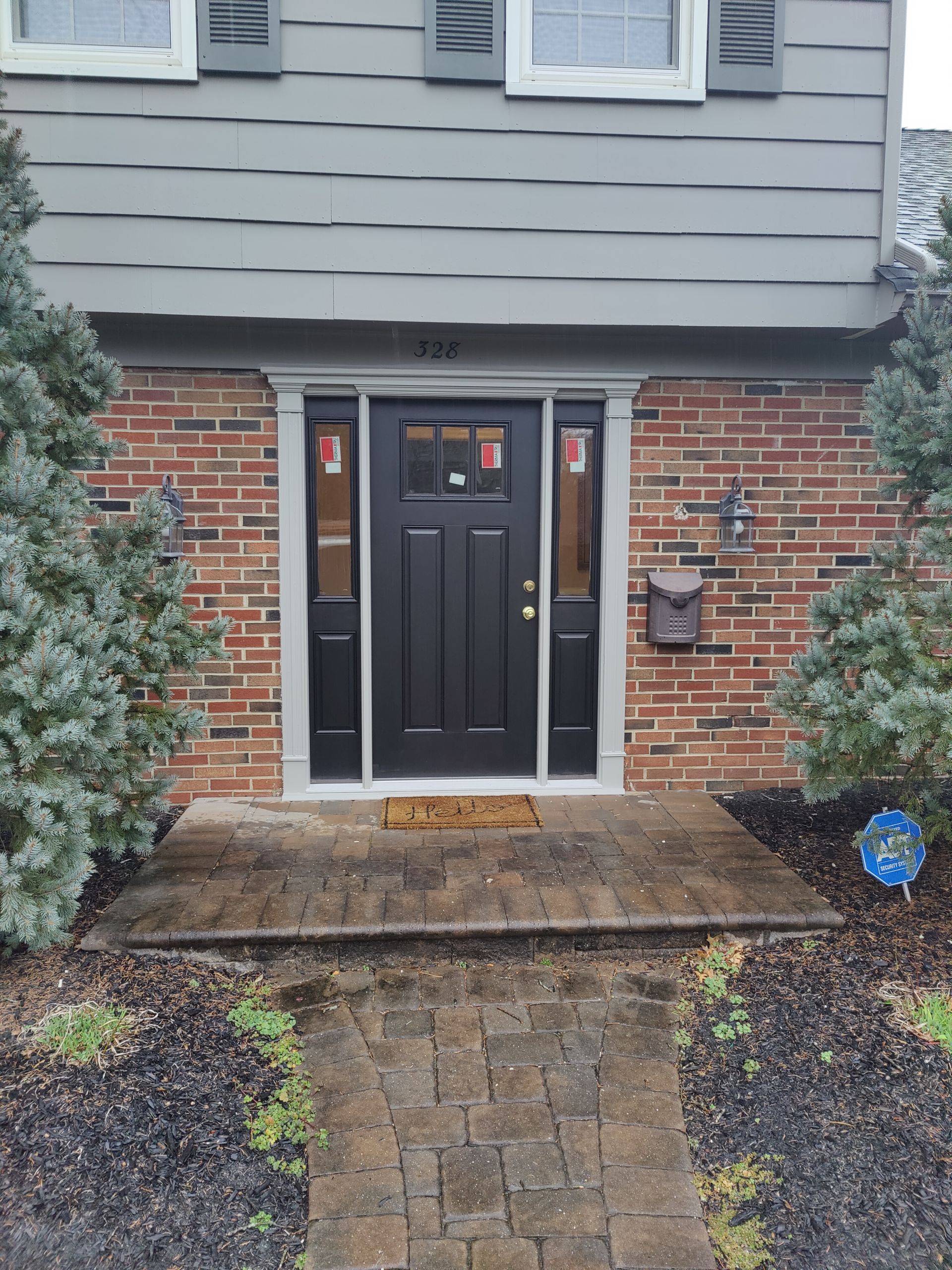 The front door of a brick house with a black door.