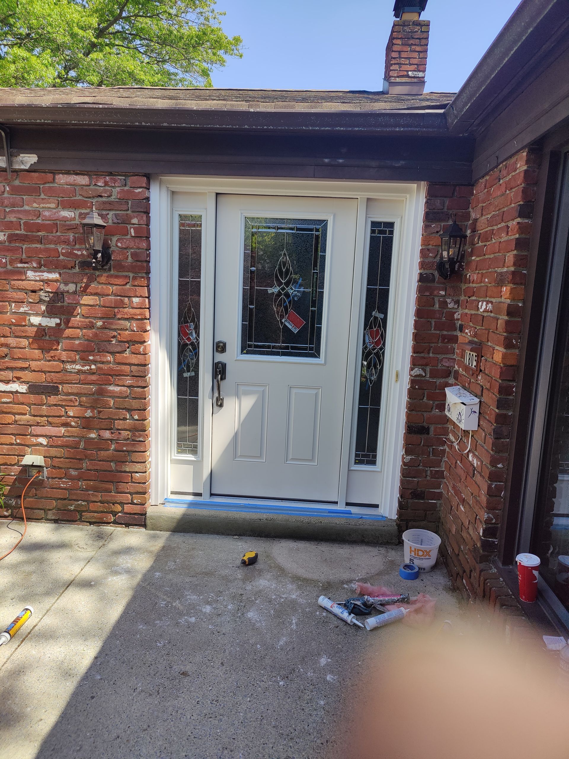 A white door is being painted on a brick house.