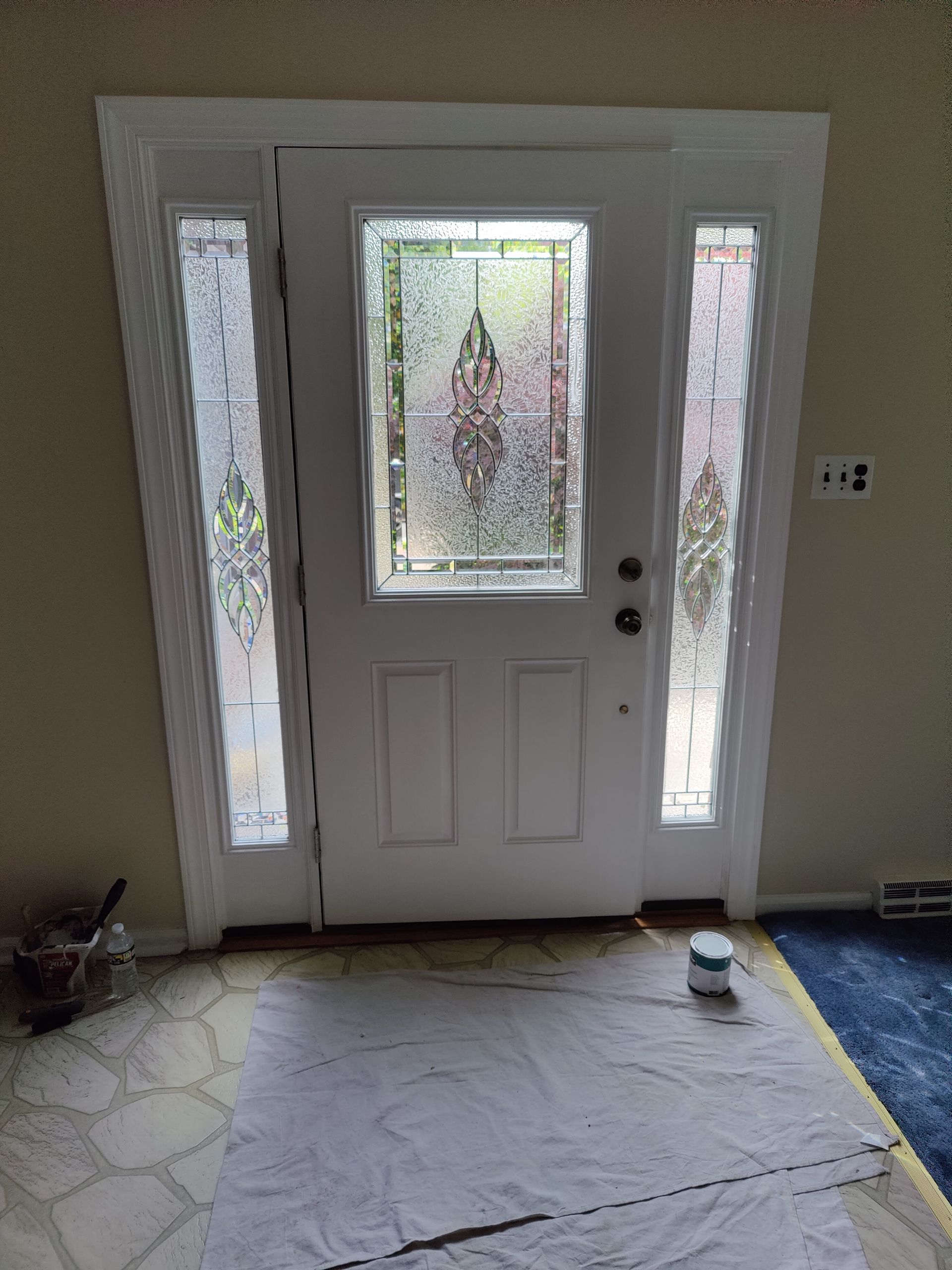 A white door with stained glass windows is being painted in a room.