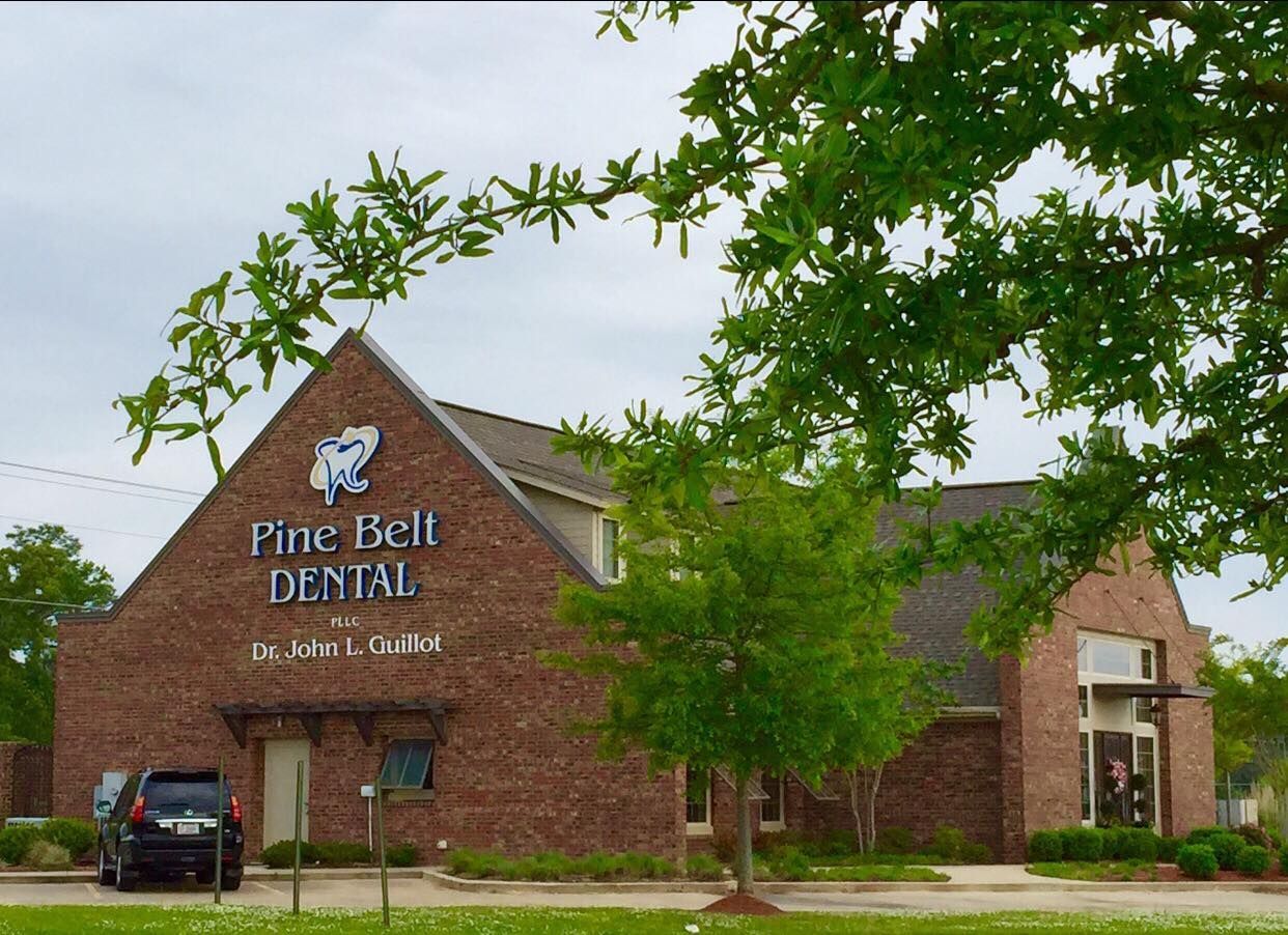 Pine Belt Dental building; brown brick exterior, green trees.