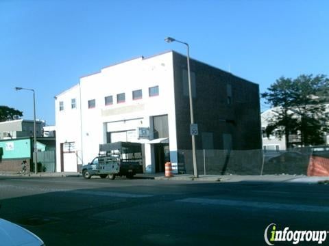 Building on a street corner with a truck parked in front, on a sunny day.