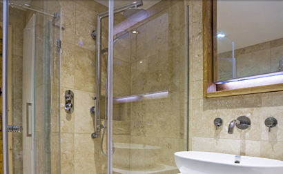 Bathroom with glass shower, white sink, and large mirror; beige tile walls.