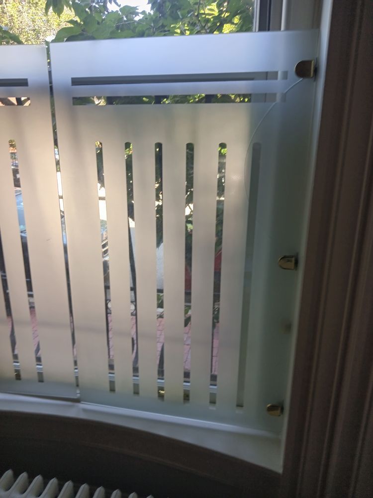 Frosted glass window with vertical cutouts. Sunlight streams through, illuminating the outside view.