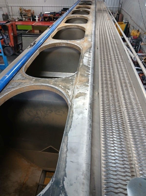 Large metal structure with oval openings and a walkway, likely industrial.