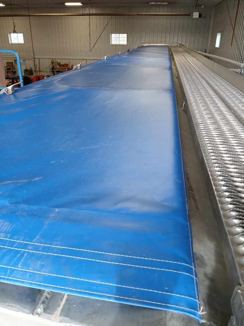 Blue tarp stretched over a metal structure indoors.