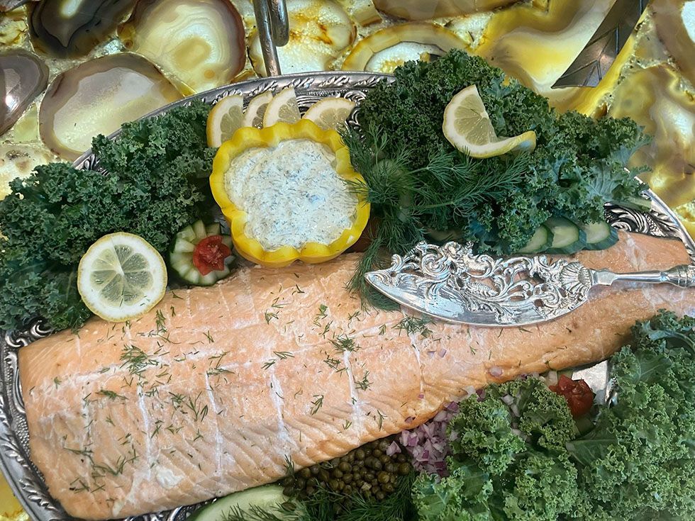 Baked salmon garnished with kale, lemon slices, and herbs on a serving platter