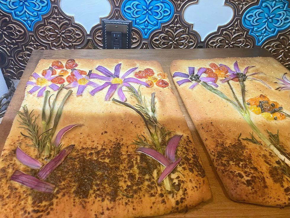 Two flower-decoracted loaves of bread on a tray
