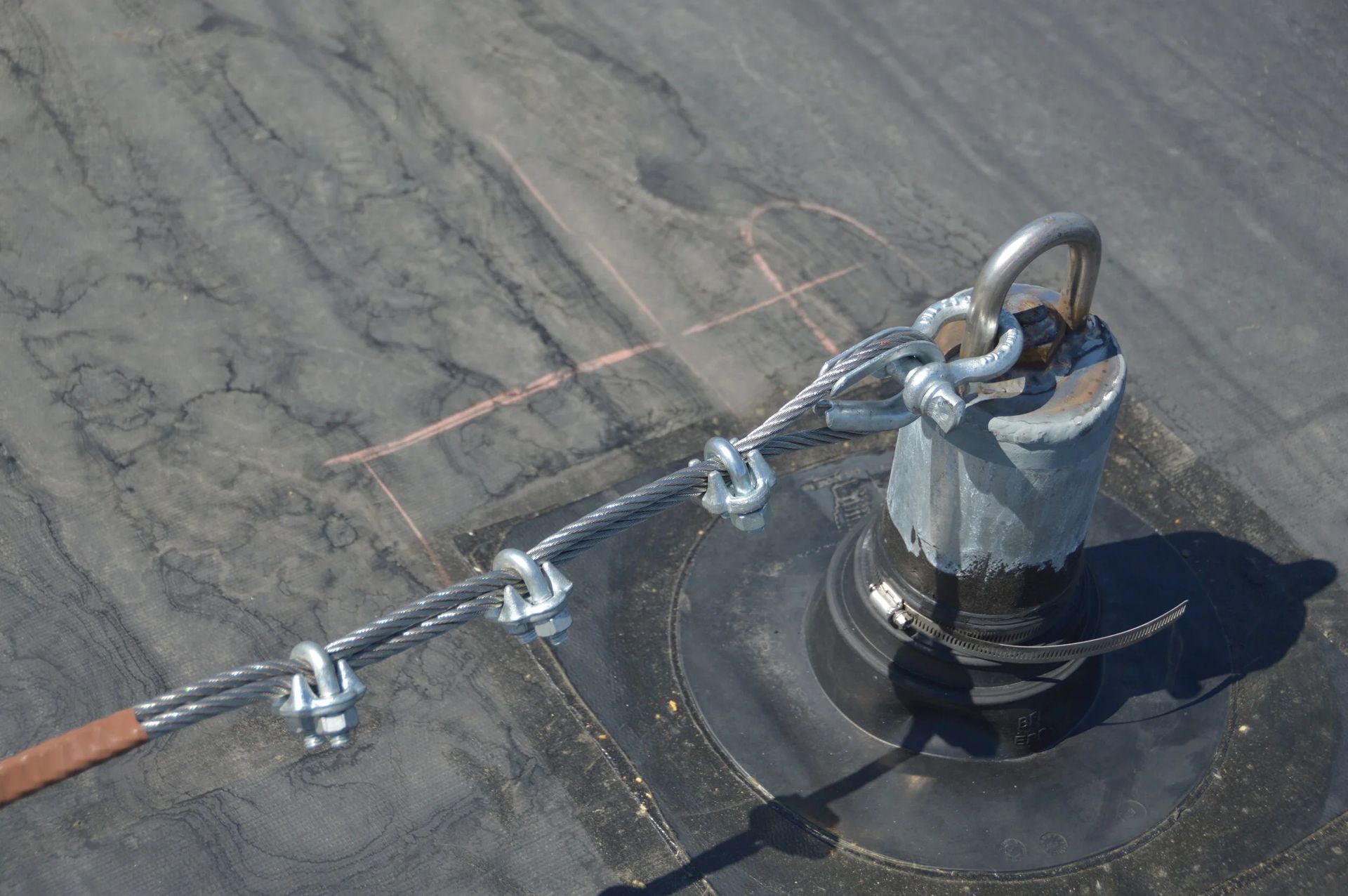 A steel cable is secured to a metal roof anchor using a thimble and three wire rope clips.