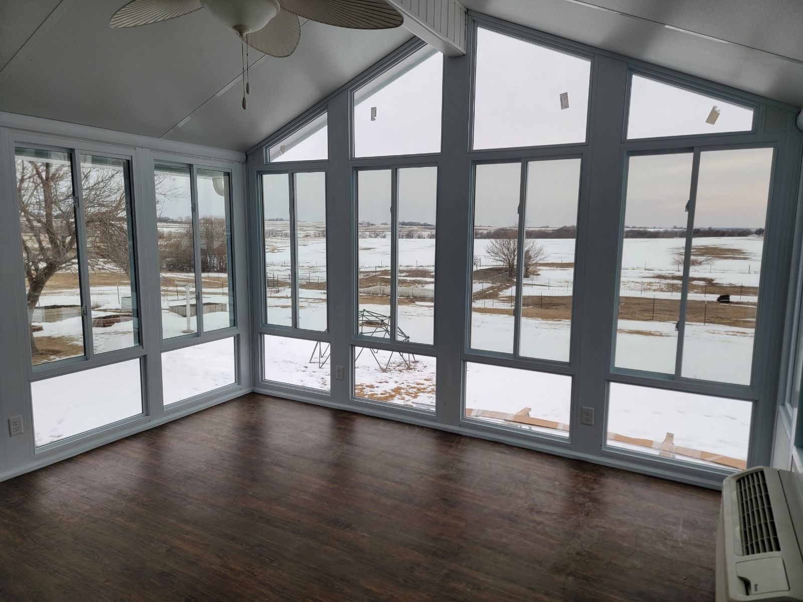 A sunroom with a lot of windows and a view of a snowy field