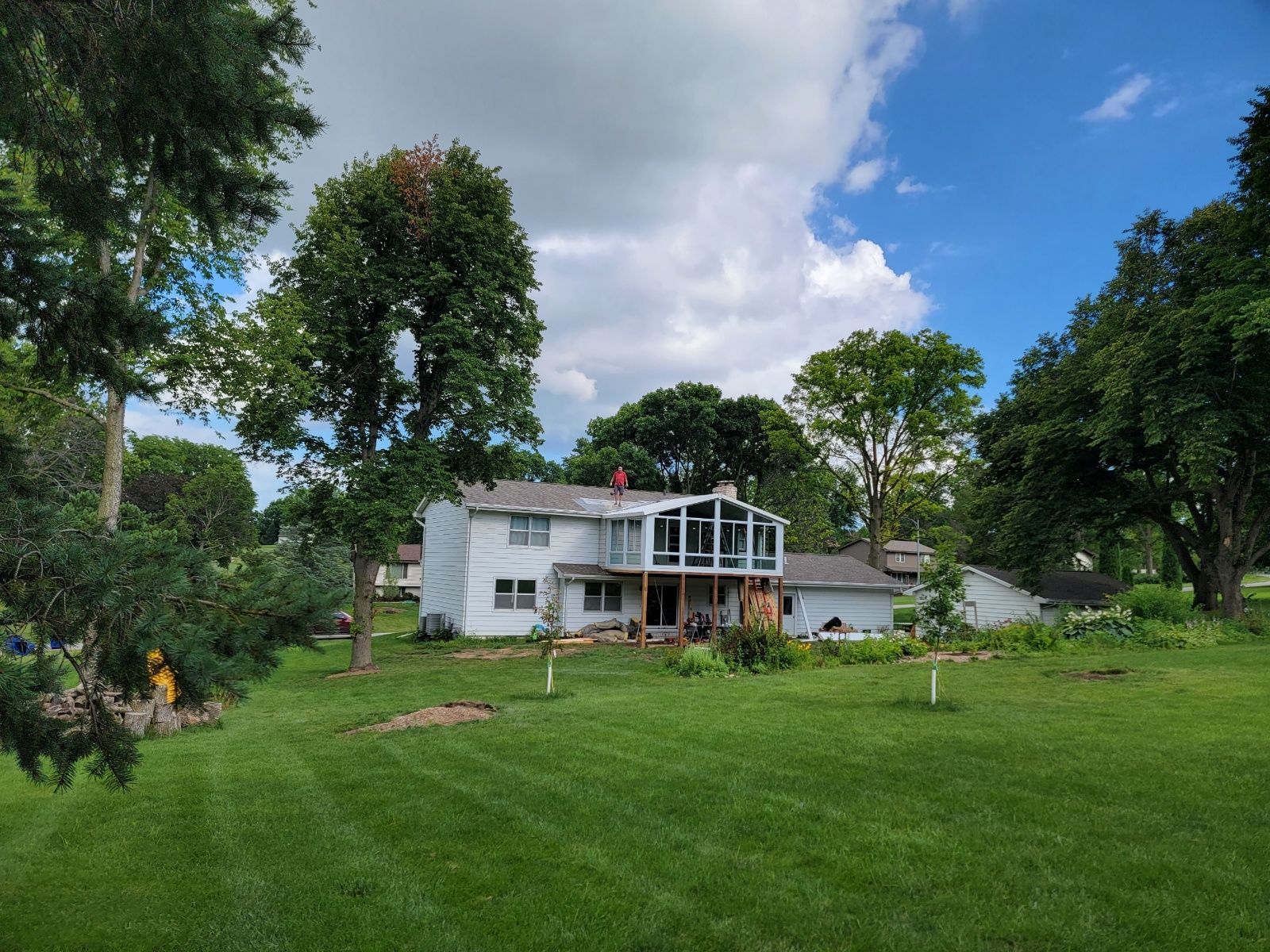 A large white house with a large lawn in front of it surrounded by trees
