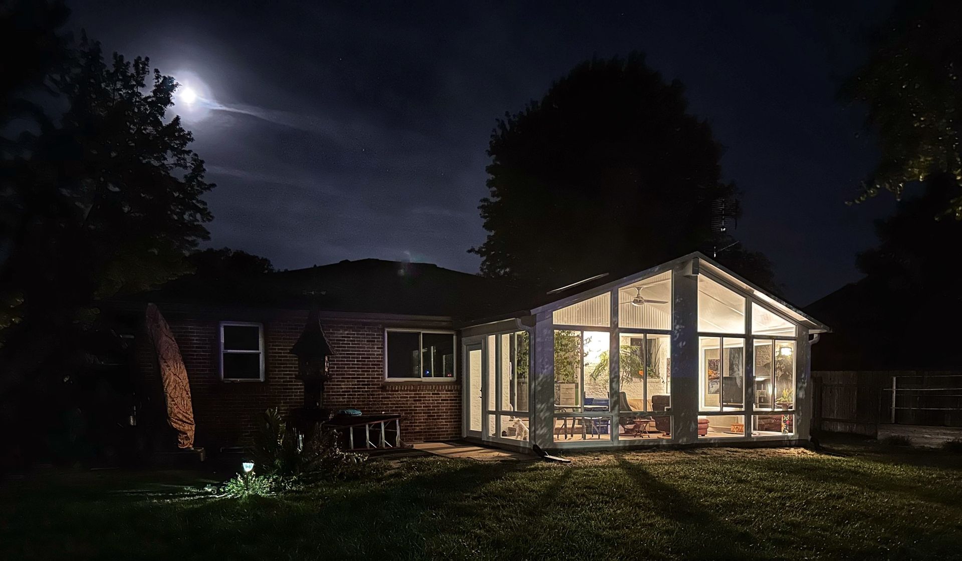 A house with a sunroom is lit up at night