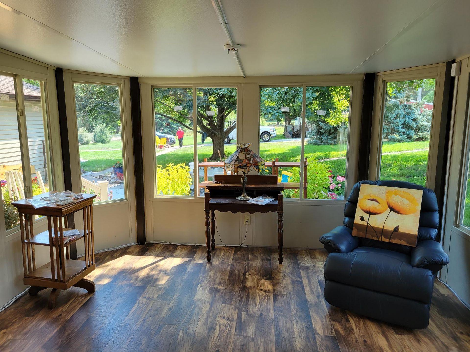 A sunroom with a chair, desk, and lots of windows