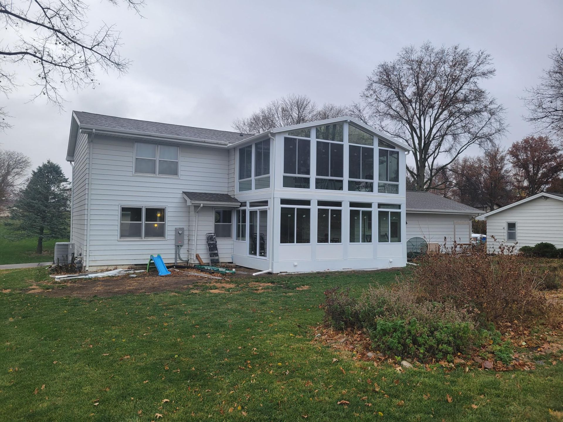 A white house with a sunroom in the backyard