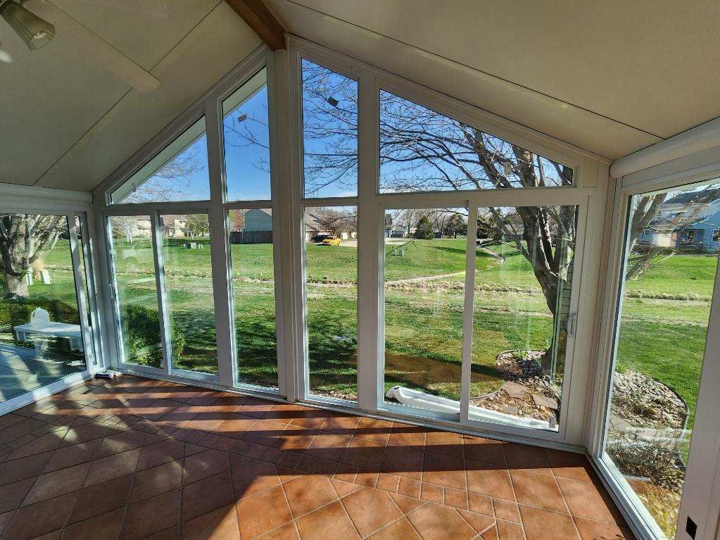 A sunroom with a lot of windows and a view of a field