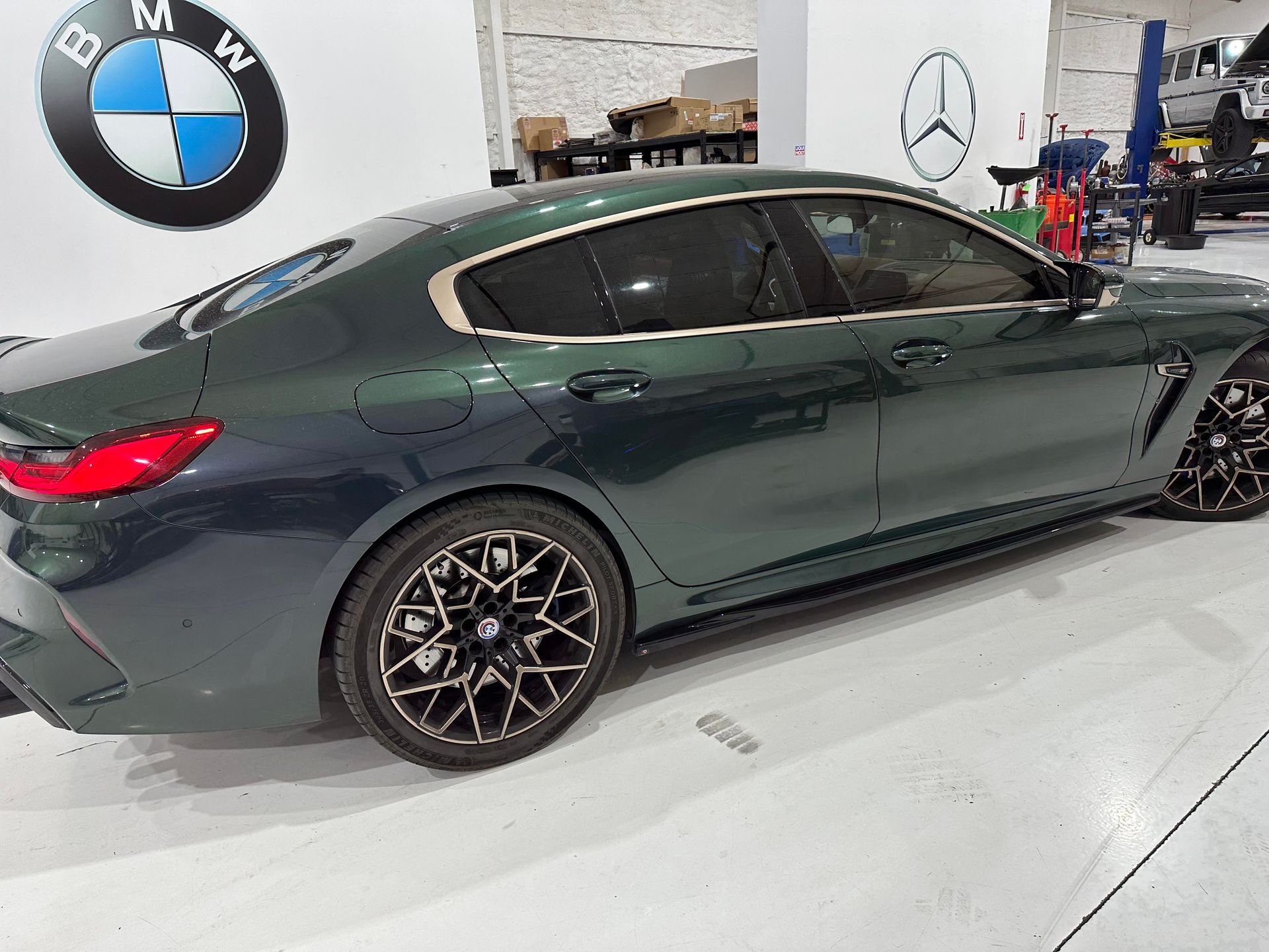 Green BMW sedan parked inside a garage, with a BMW logo on the wall.