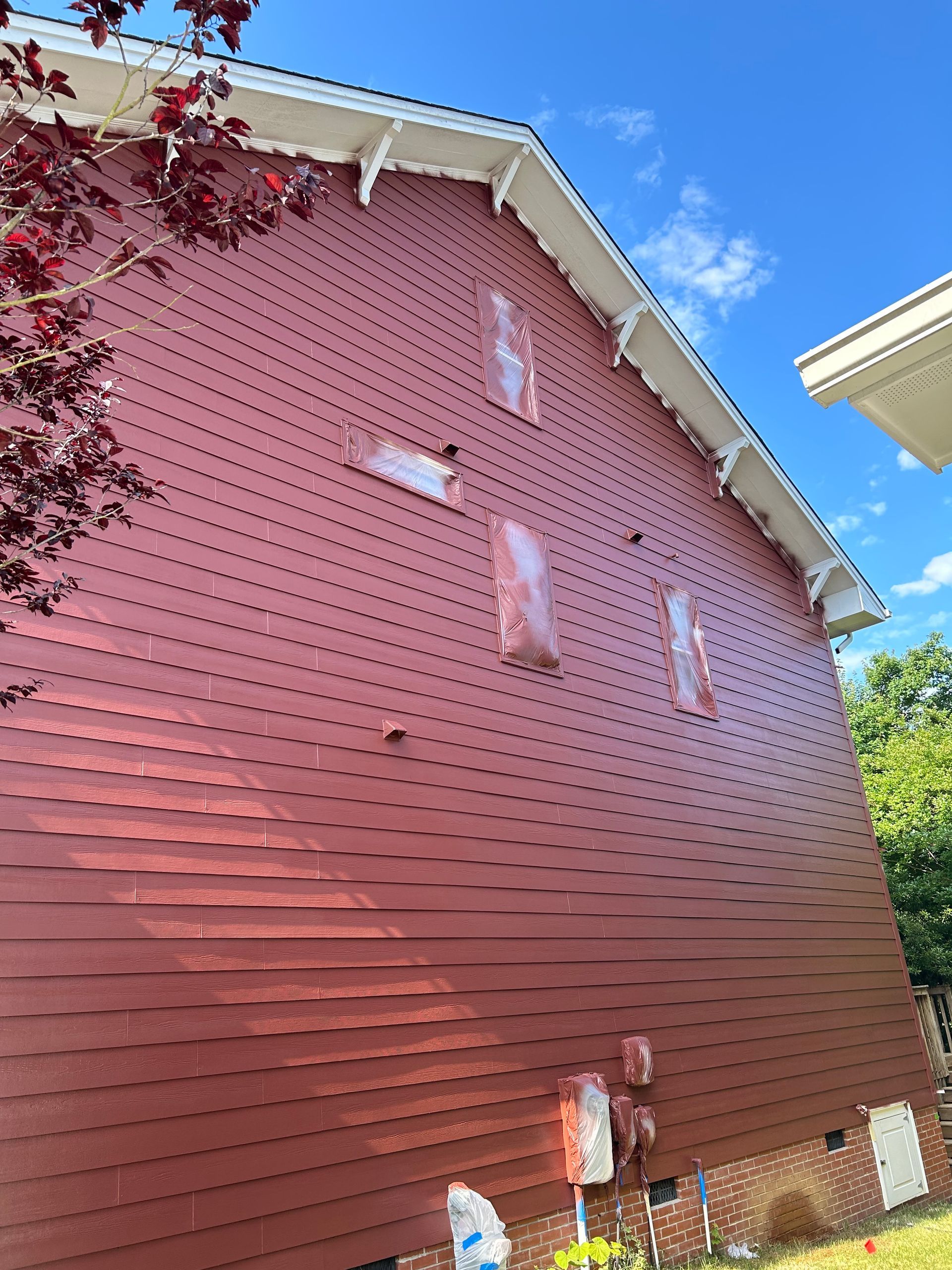 A red house with a blue sky in the background is being painted