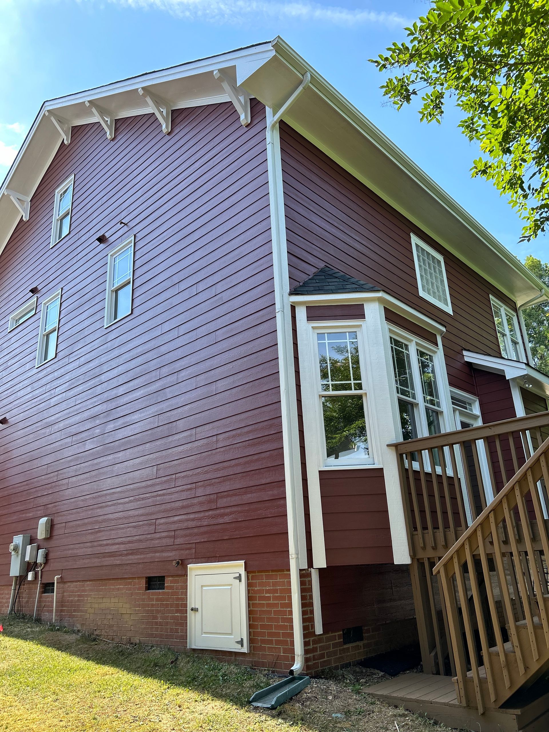 A red house with a wooden deck and stairs