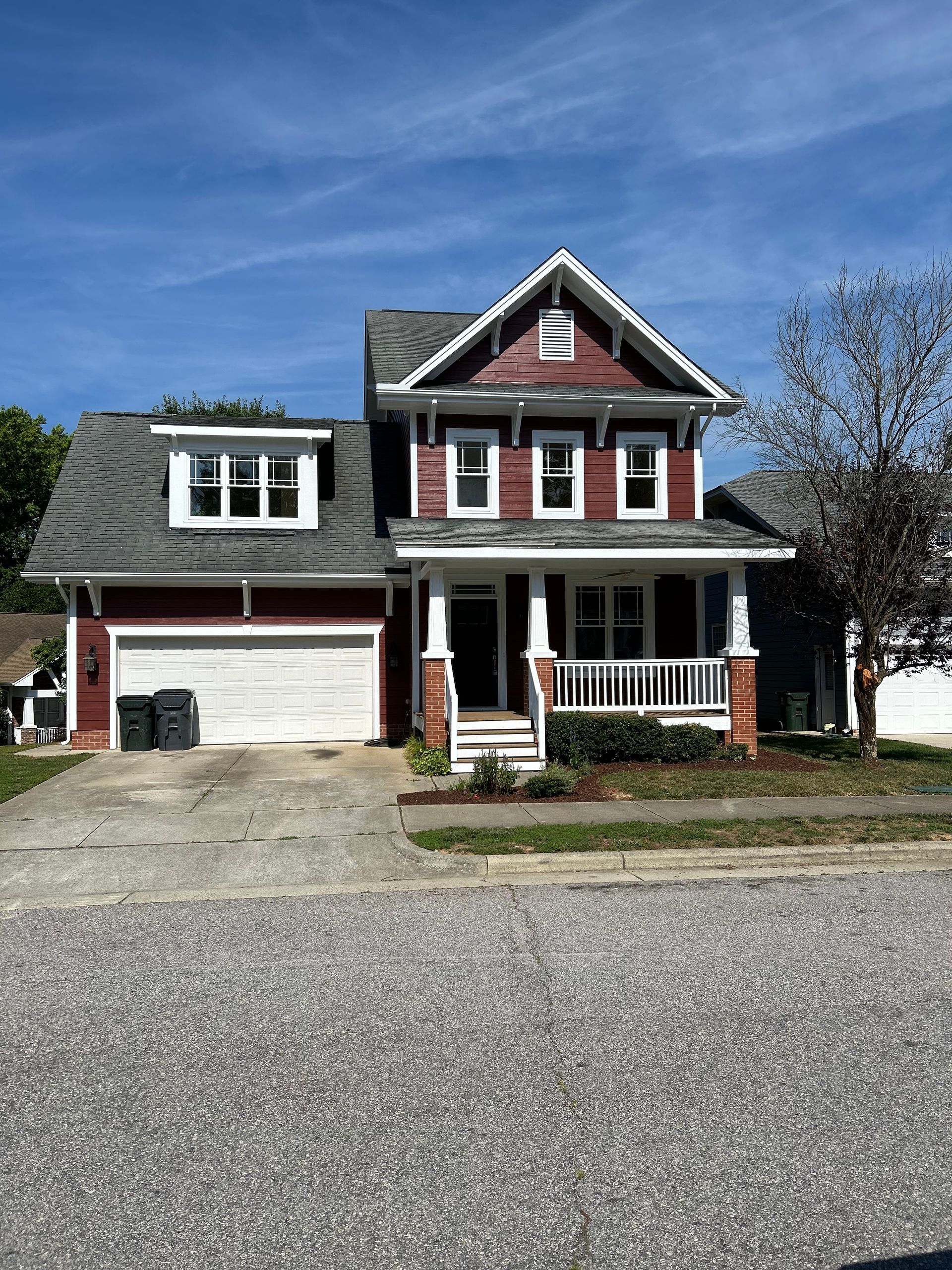 A large red and white house with a gray roof and a white garage door