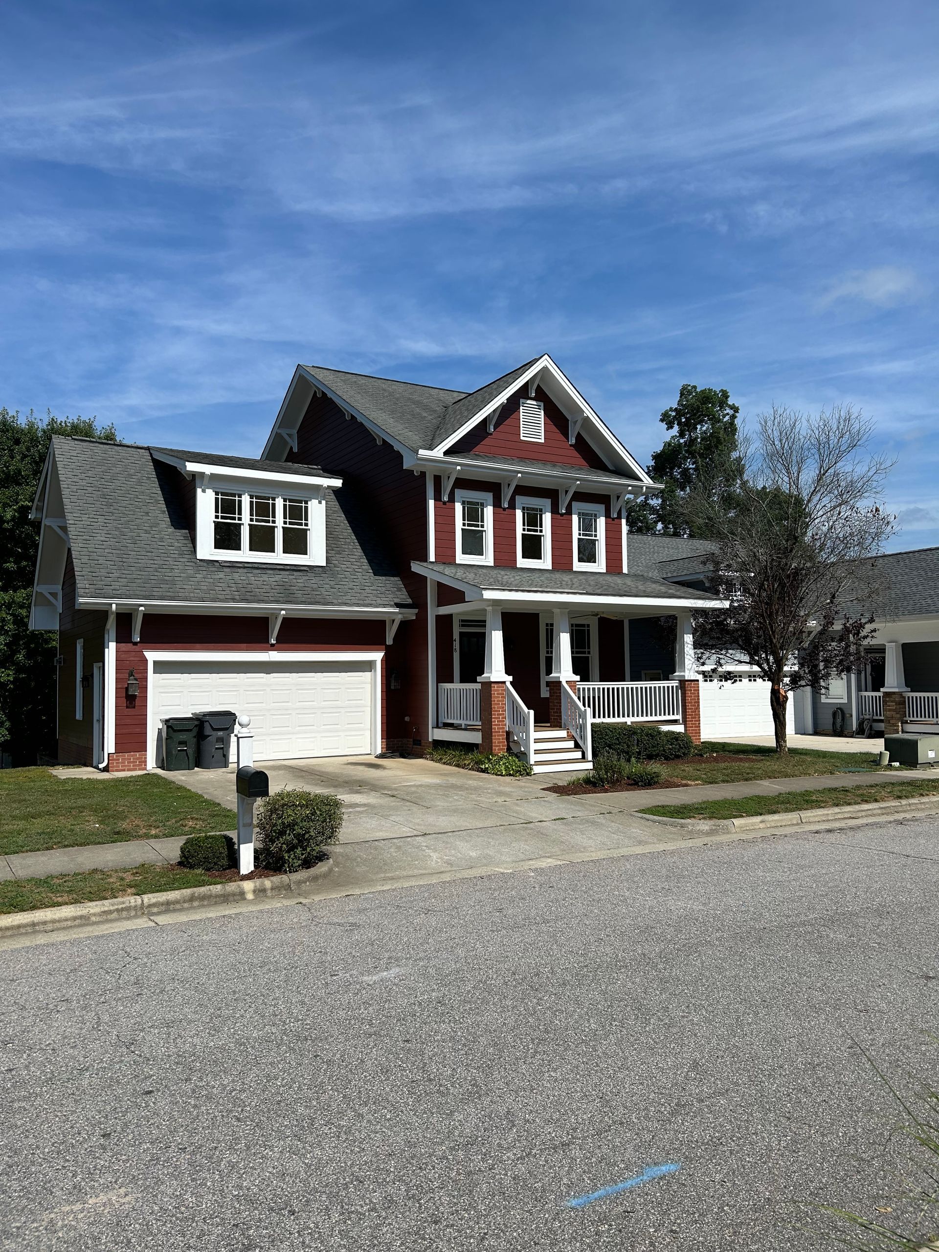 A red and white house with a gray roof and a mailbox in front of it