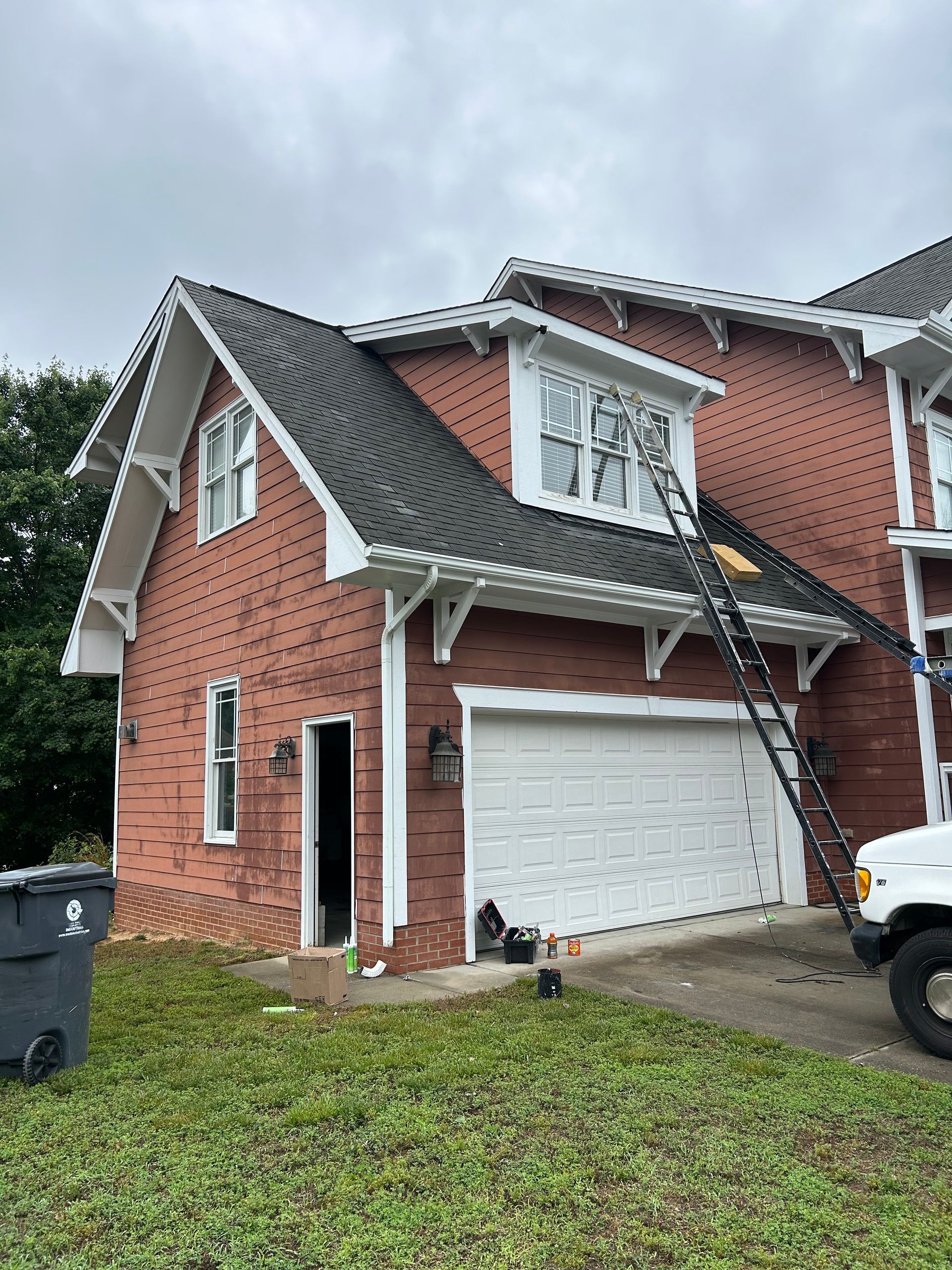 A red brick house with a white garage door and a white truck parked in front of it