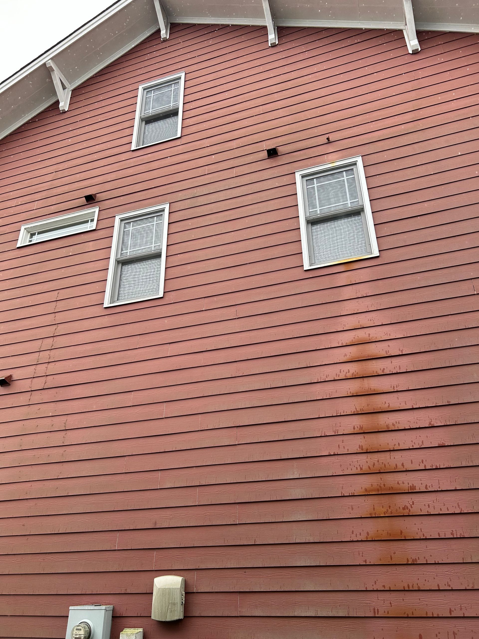 A red brick building with three windows and a roof