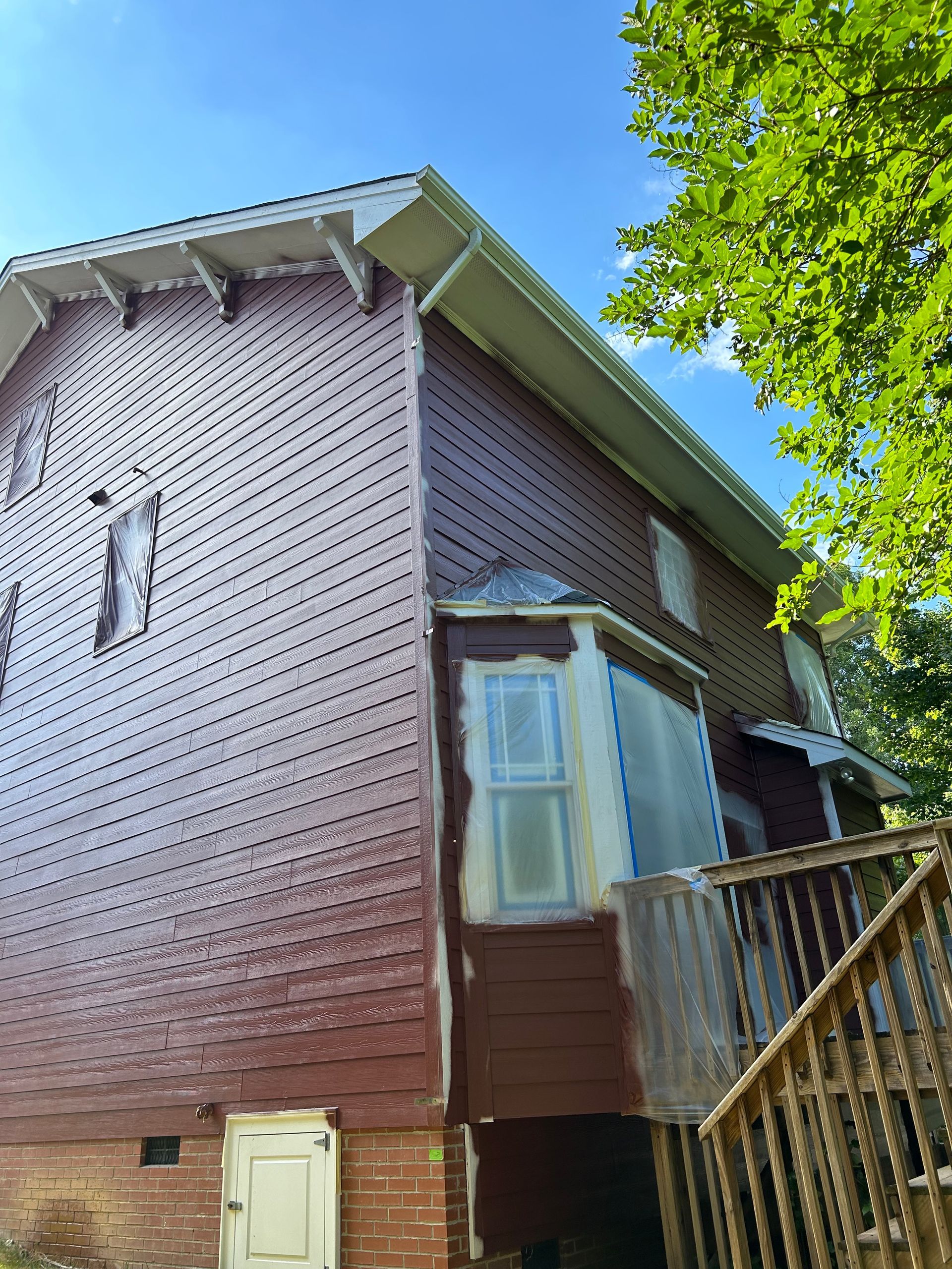 The side of a brick house is being painted red