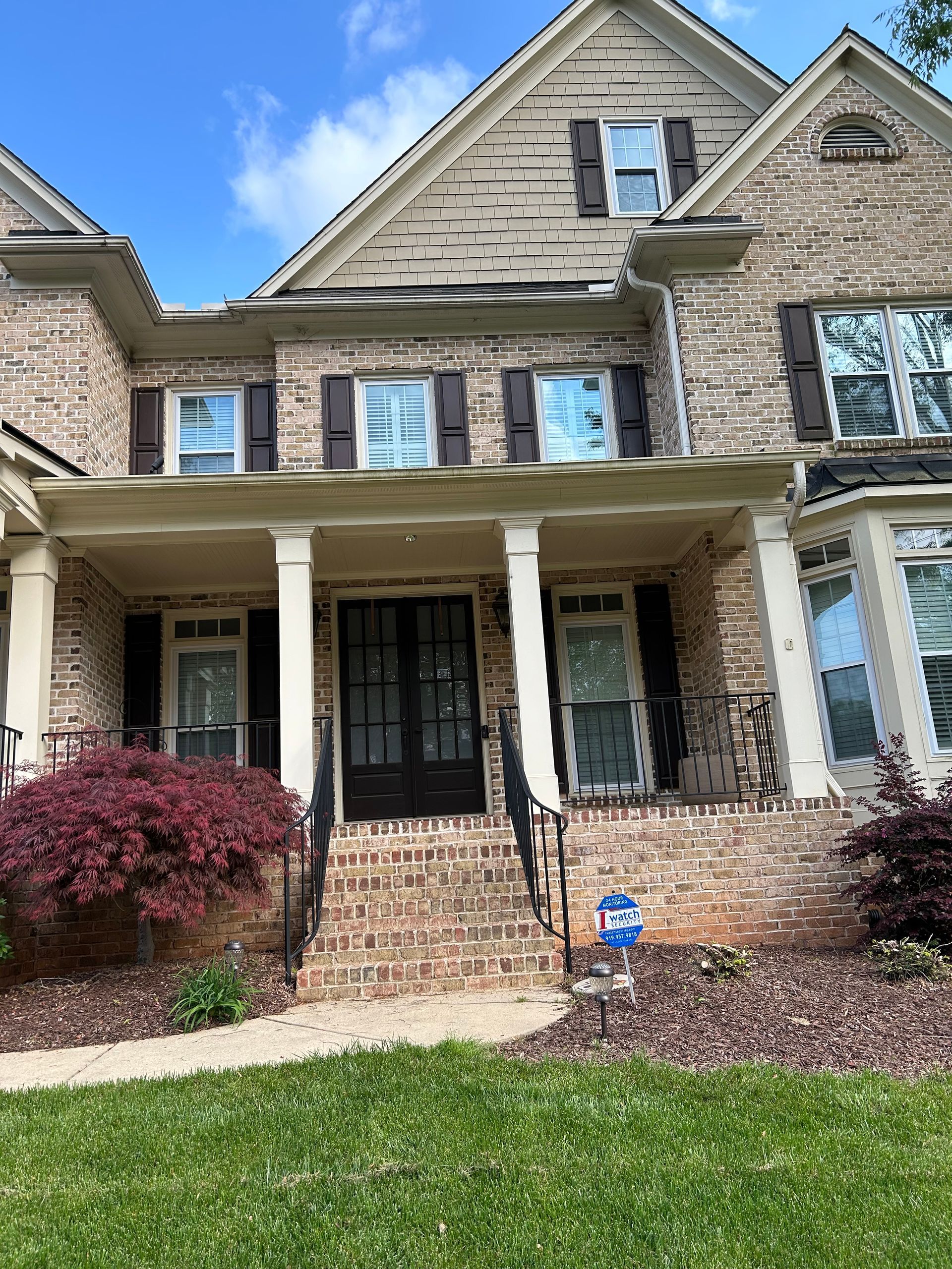 A large brick house with black shutters and a large porch